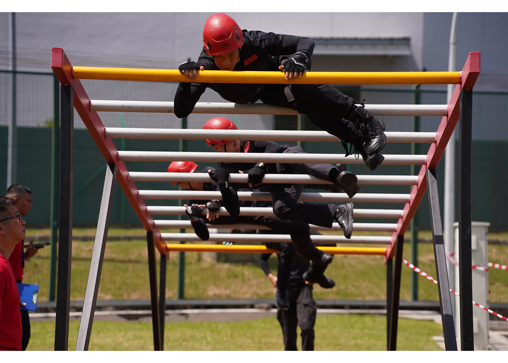 A team of officers traversing across the "wave", an obstacle that looks like a wide ladder placed horizontally and elevated about 4-feet off the ground. Officers have to traverse through by climbing over and under the series of ladder without touching the ground.