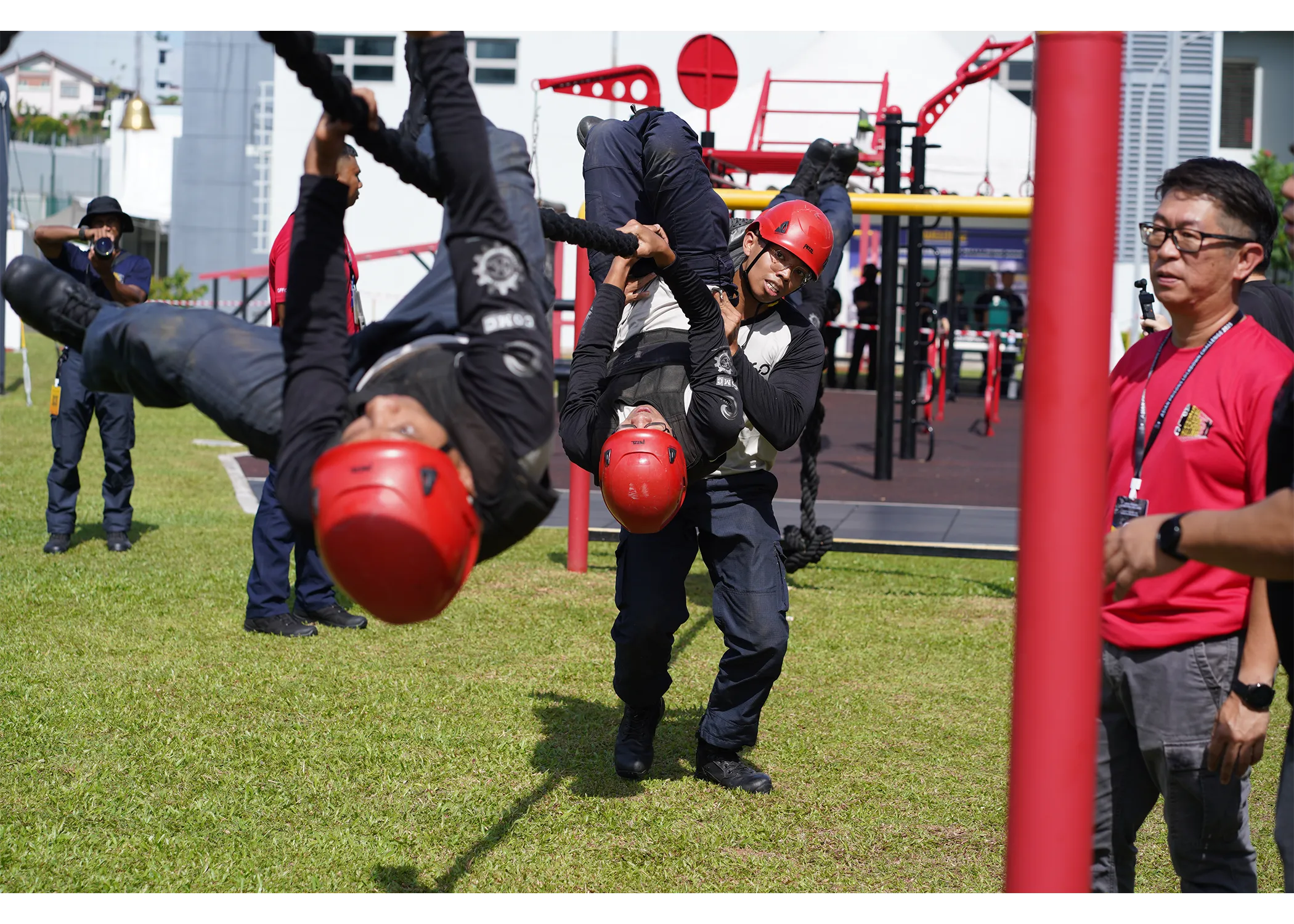 A team of officers hanging upside down the commando rope, hanging by their hands and feet in their attempt to climb over to the other side