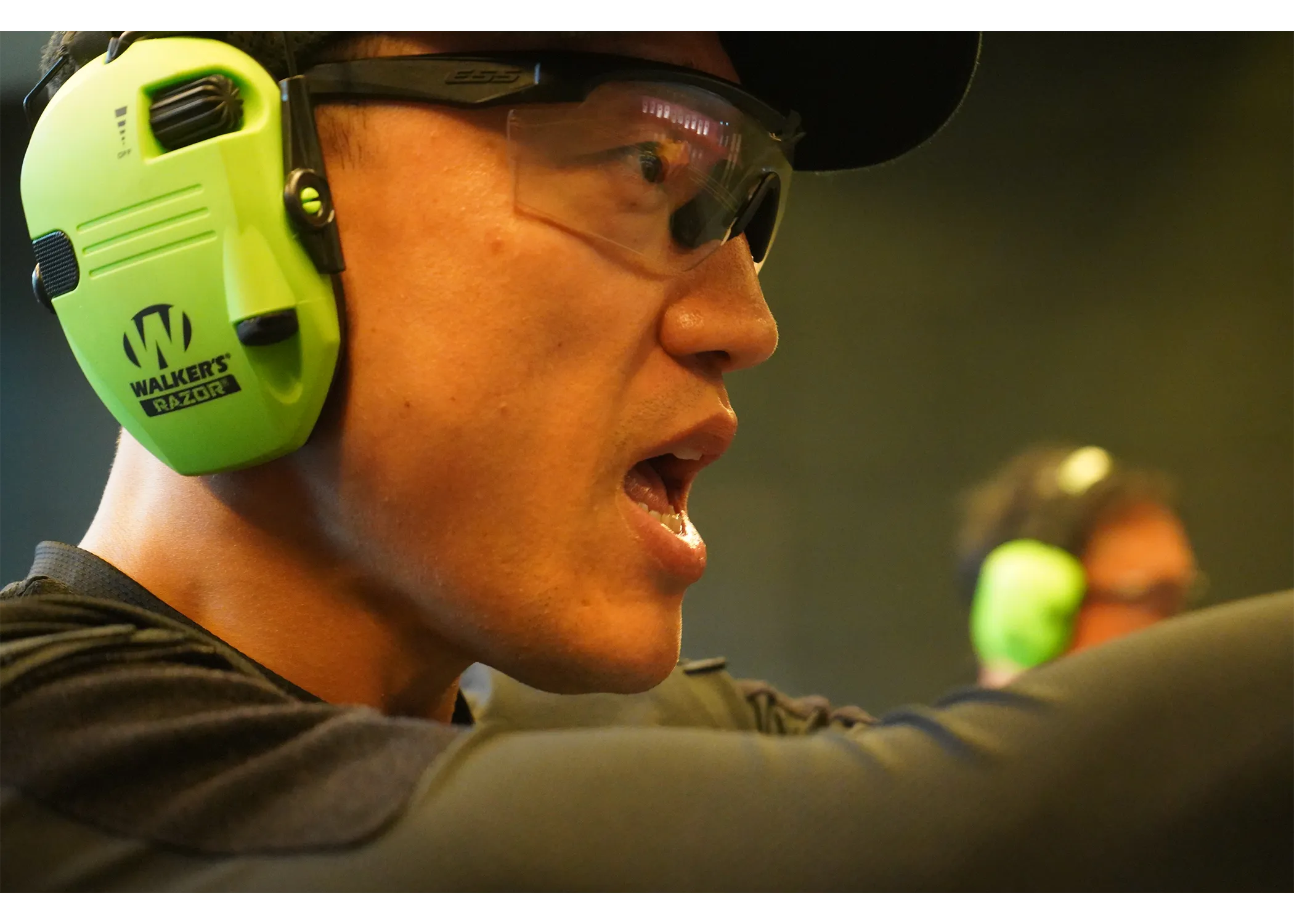 Close up photograph of an officer's side view in the indoor shooting range with ear muffle on. 