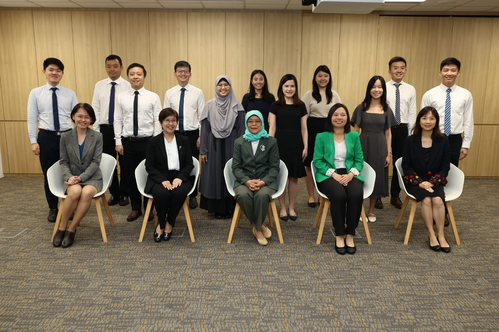 A group of people is posing in a room; some are seated and others are standing.