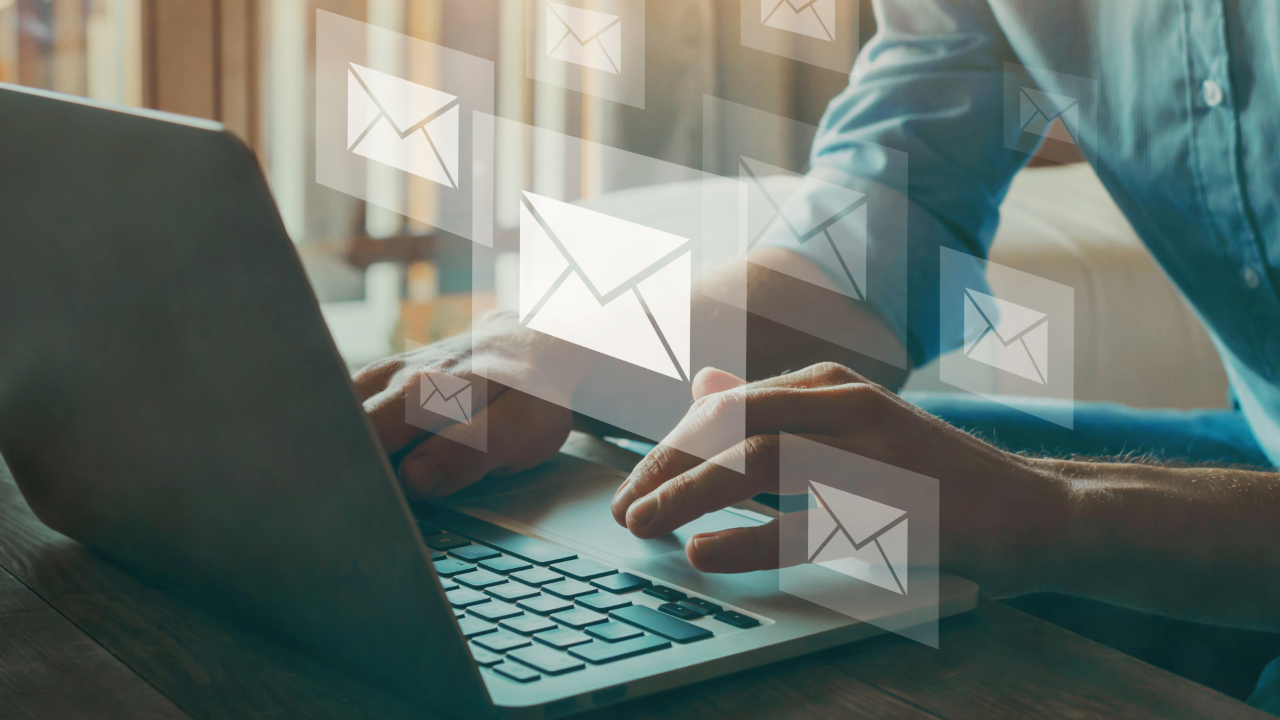 Hands typing on a laptop, with floating envelope icons suggesting email messages coming in.