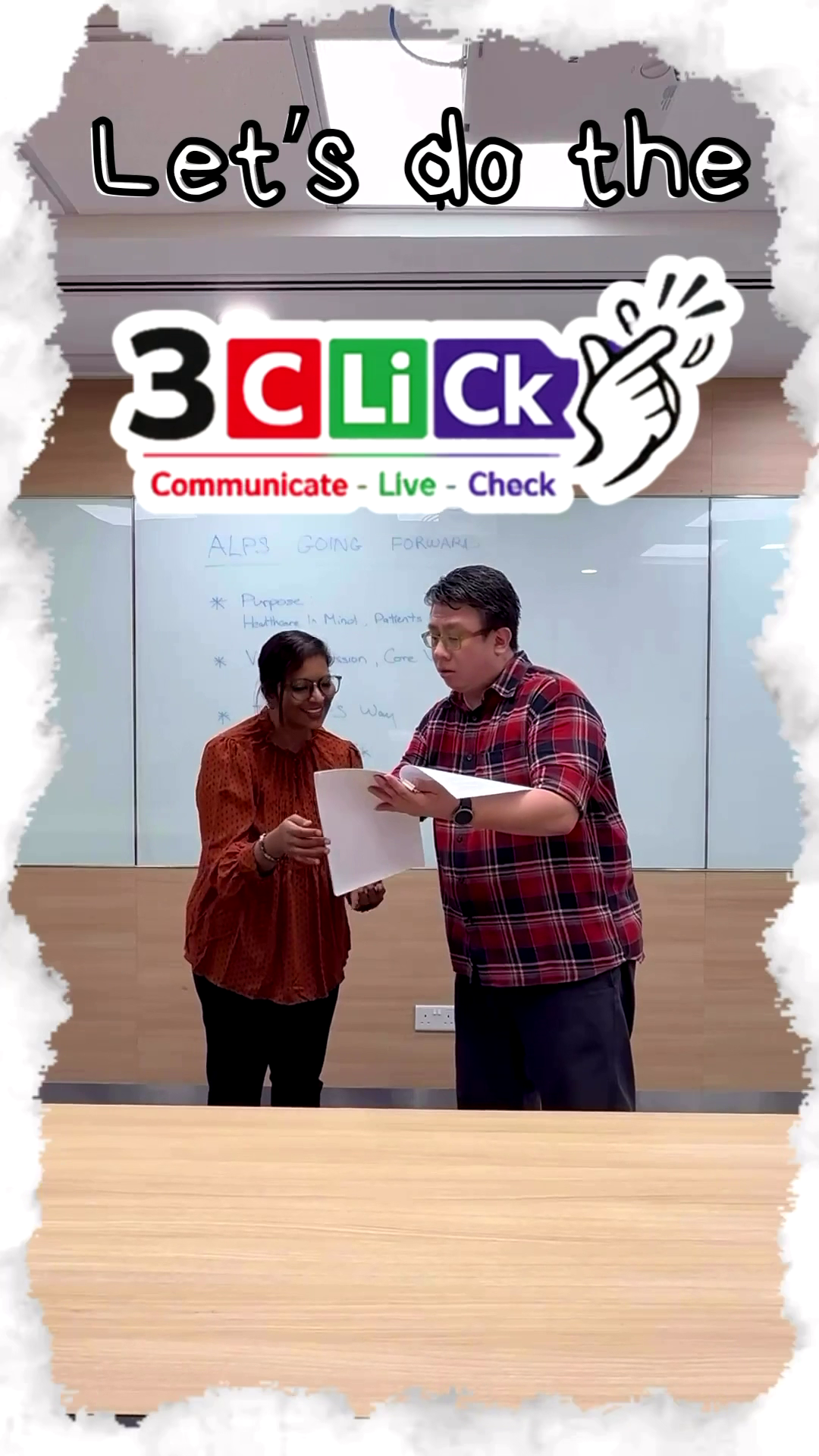 Screenshot from the '10 Safe Meeting Practices' video skit featuring two smiling colleagues reviewing documents together in a meeting room in front of a whiteboard.