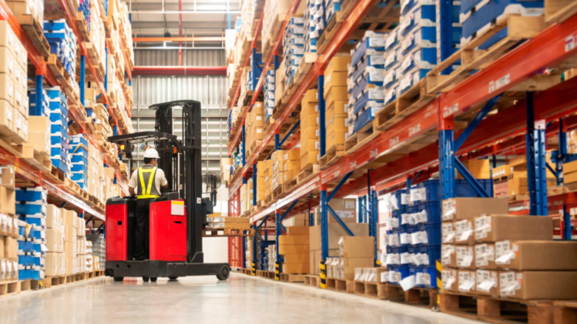 A warehouse with tall racks of boxes and a worker operating a forklift.