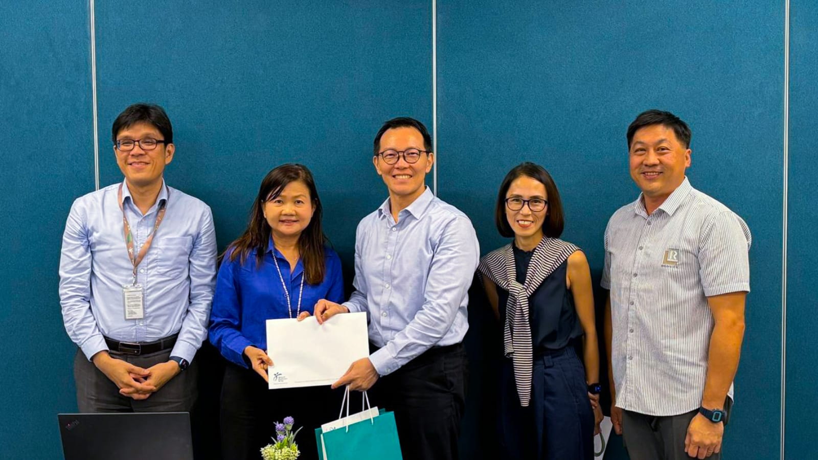 A photo showing a team of 4 ALPS representatives posing with Mr Darion Chong, Chief, Corp Services, Risk & Compliance, NHG.