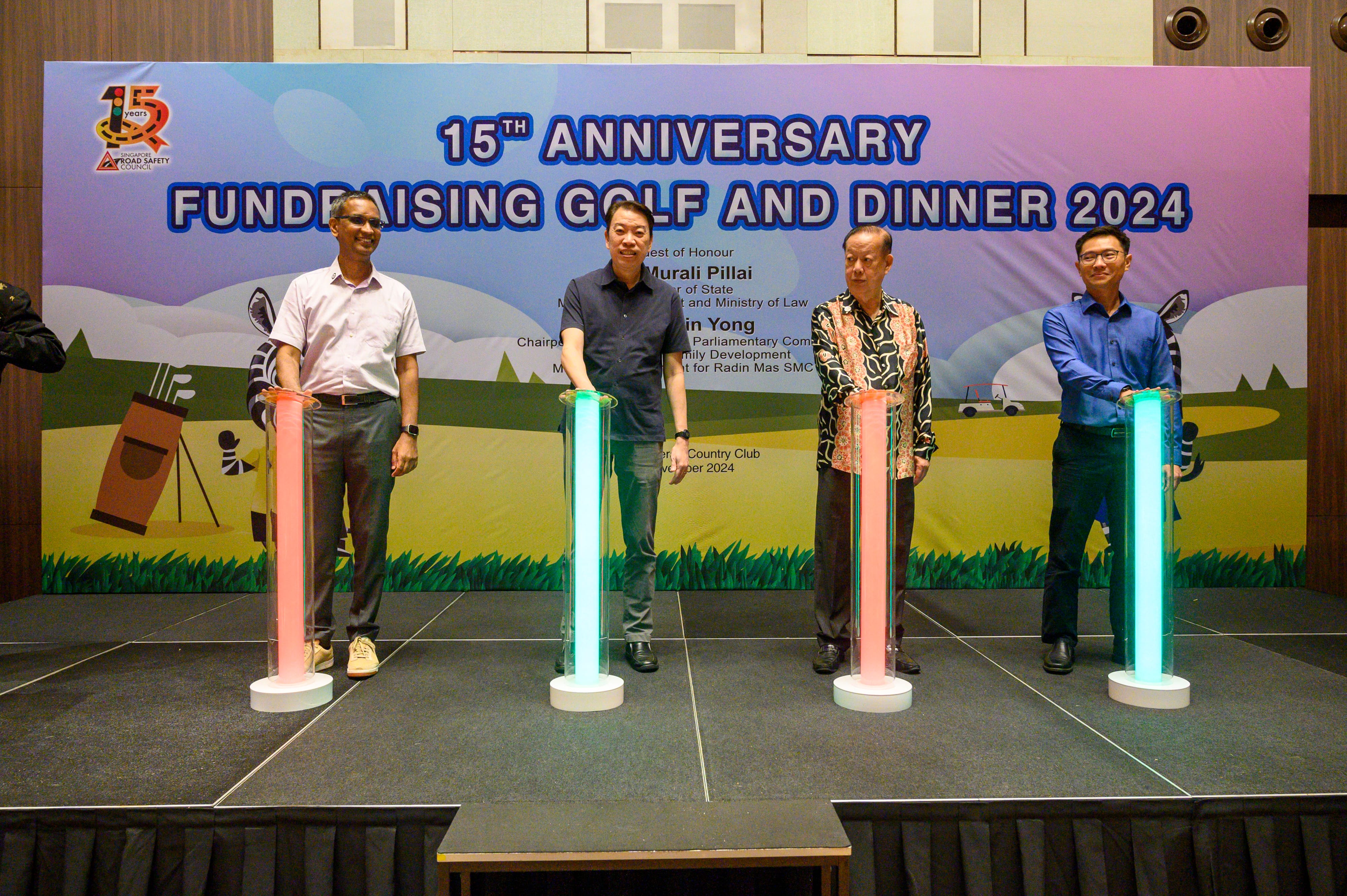 Four individuals stand behind illuminated pillars on stage at a golf and dinner fundraising event marking its 15th anniversary.
