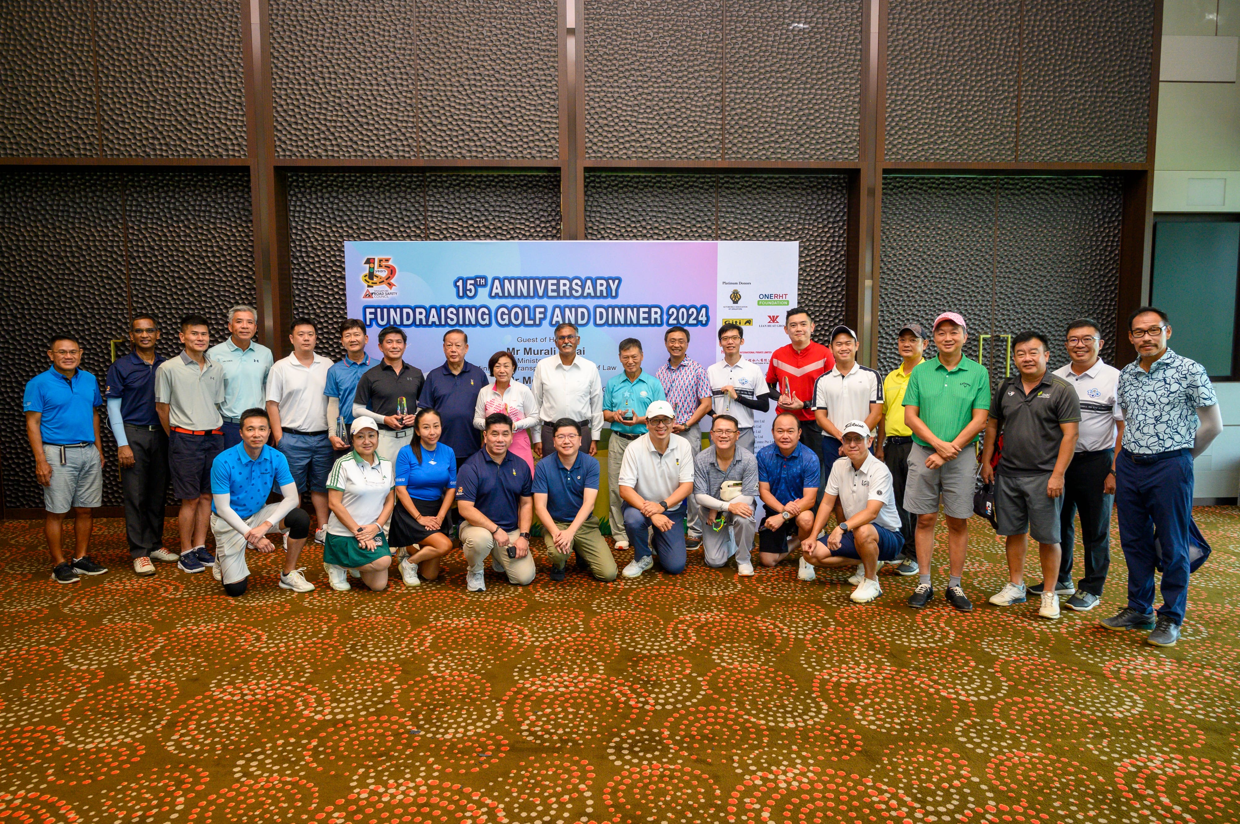 Group of people standing and sitting in front of a banner that reads "15th Anniversary Fundraising Golf and Dinner 2024".