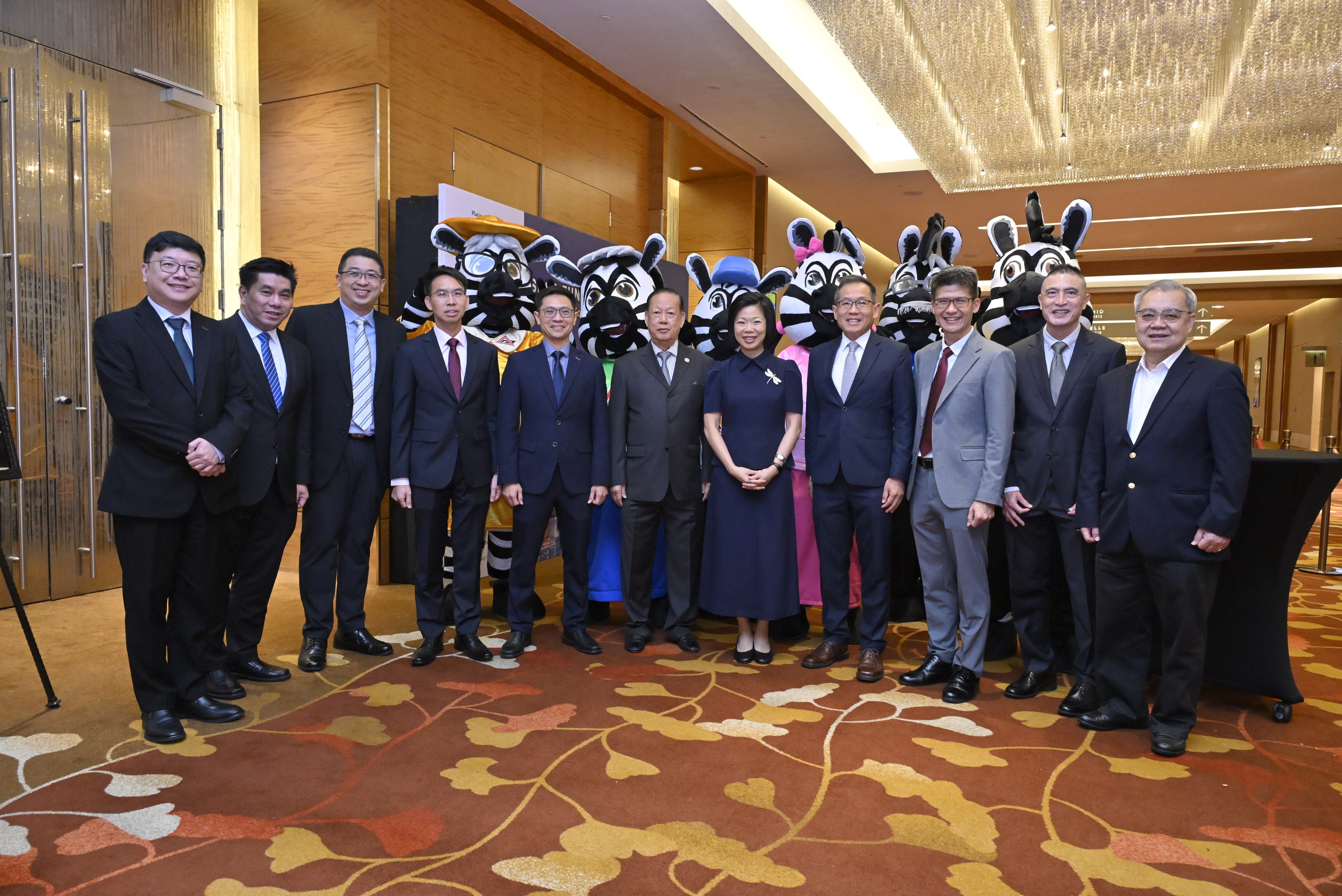 A group of people in formal attire standing indoors, with individuals in zebra costumes behind them.