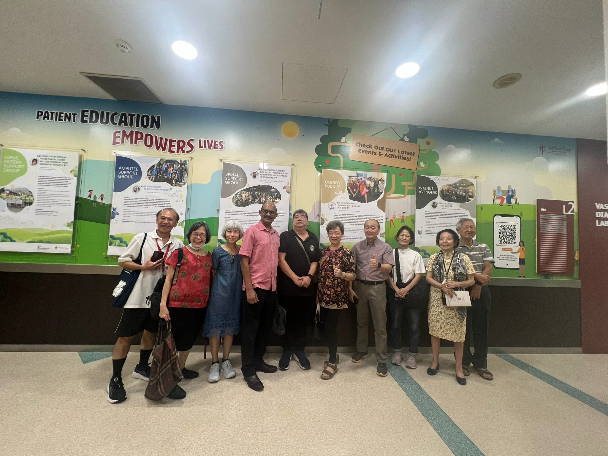 A group of people standing in front of a colorful wall displaying information about various support groups.