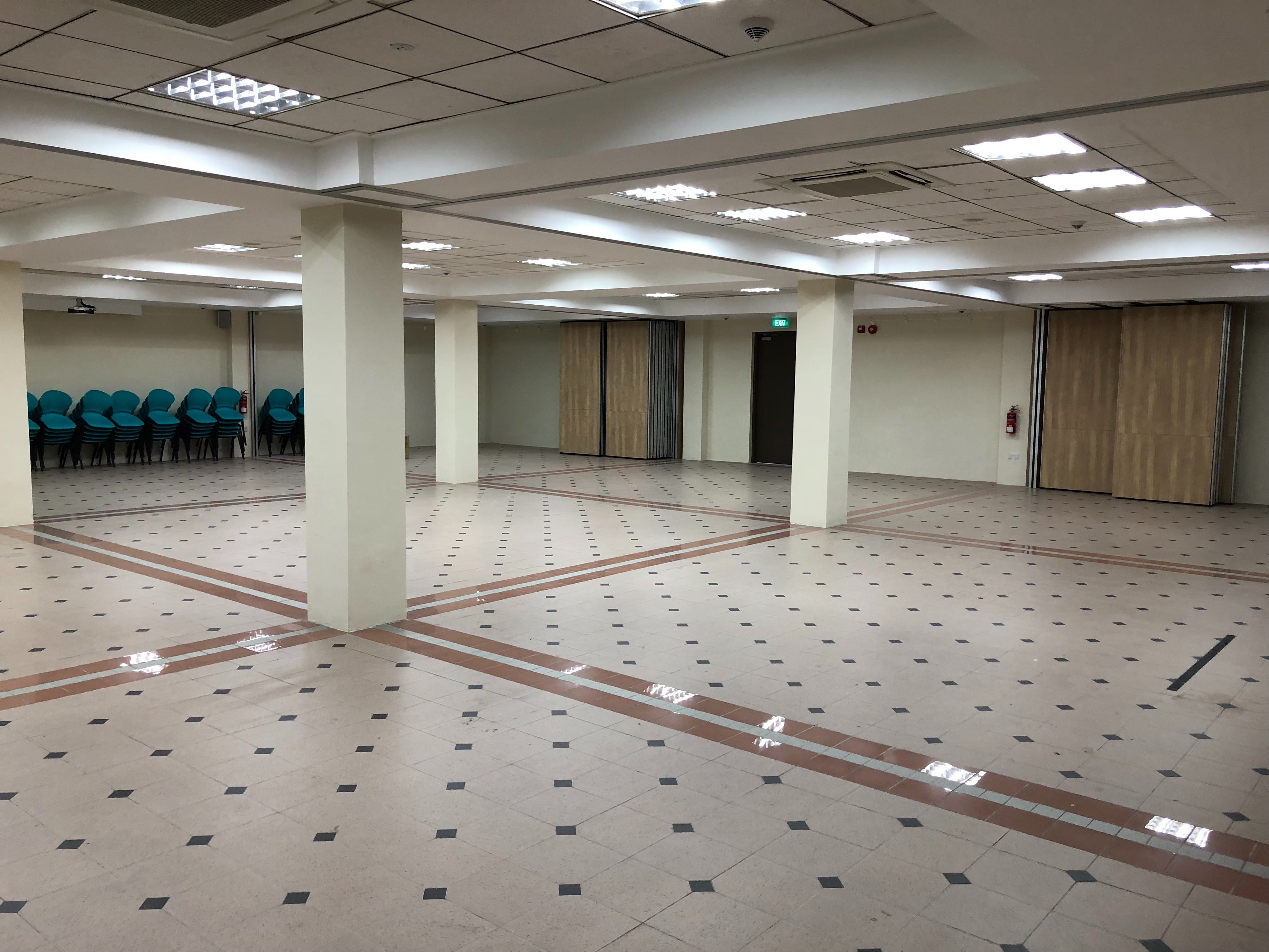 Exhibition hall with open floor space, pillars and stacked chairs.