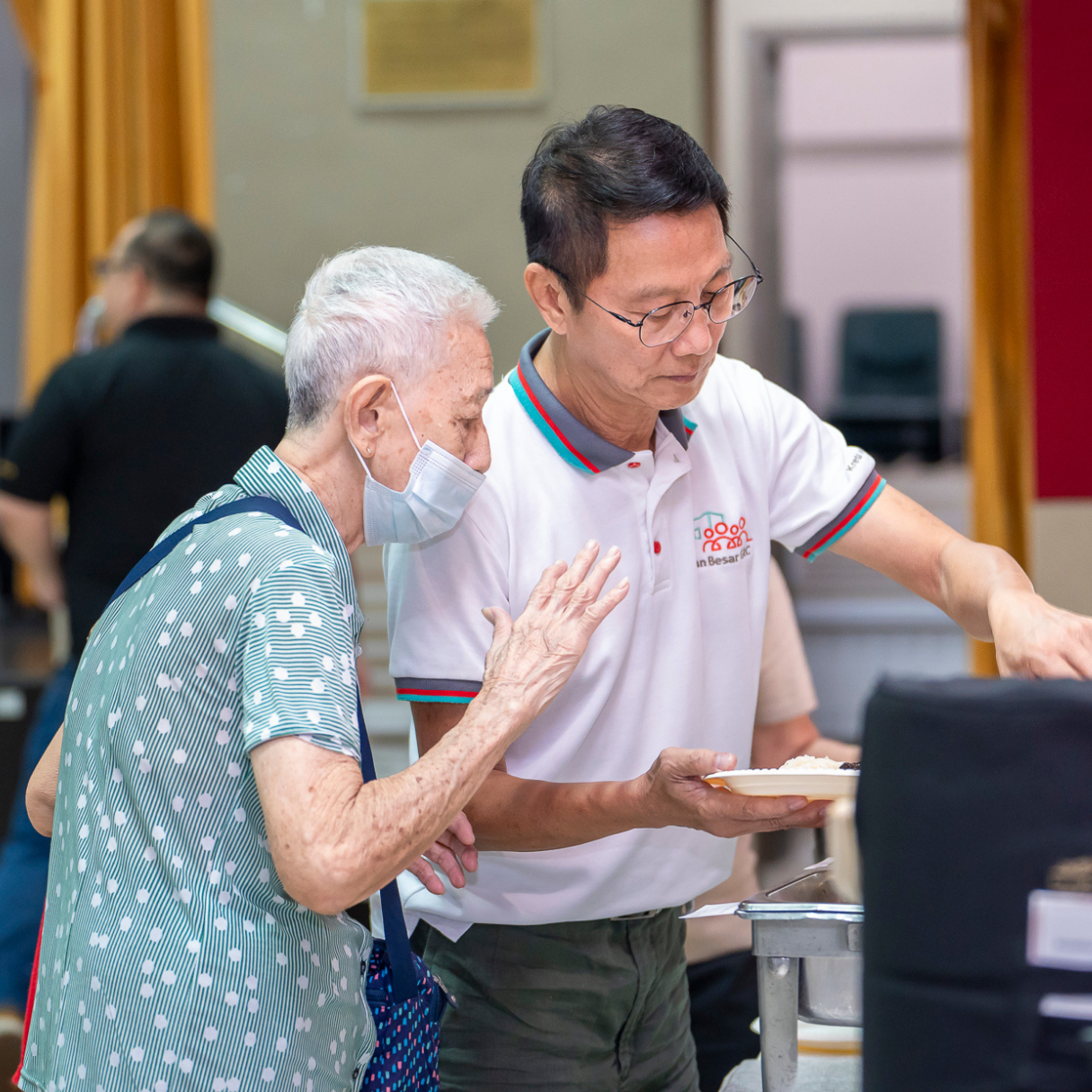 Grassroots leader helps senior choose a meal at a community event.