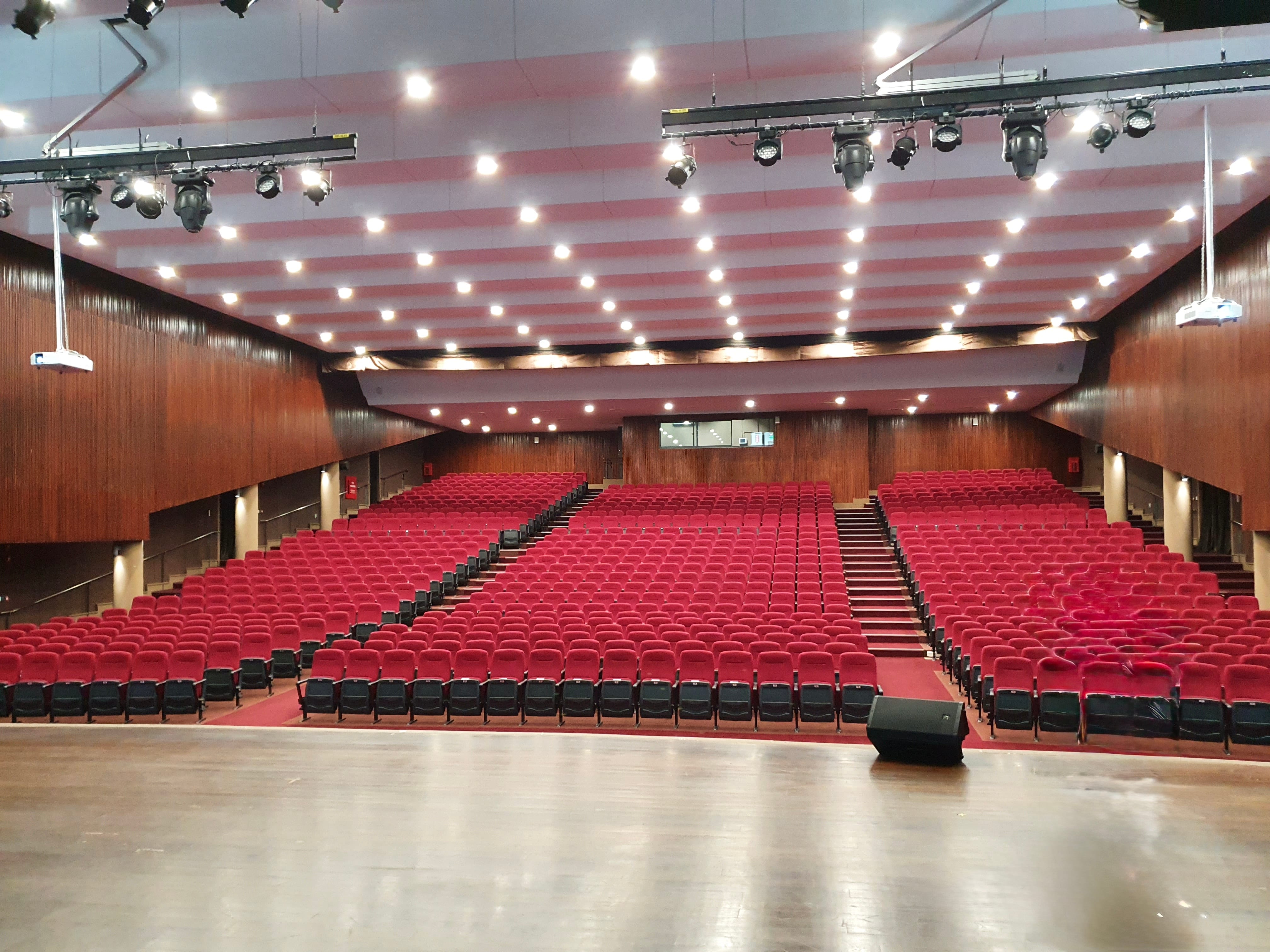 View from theatre stage showing rows of red audience seats.