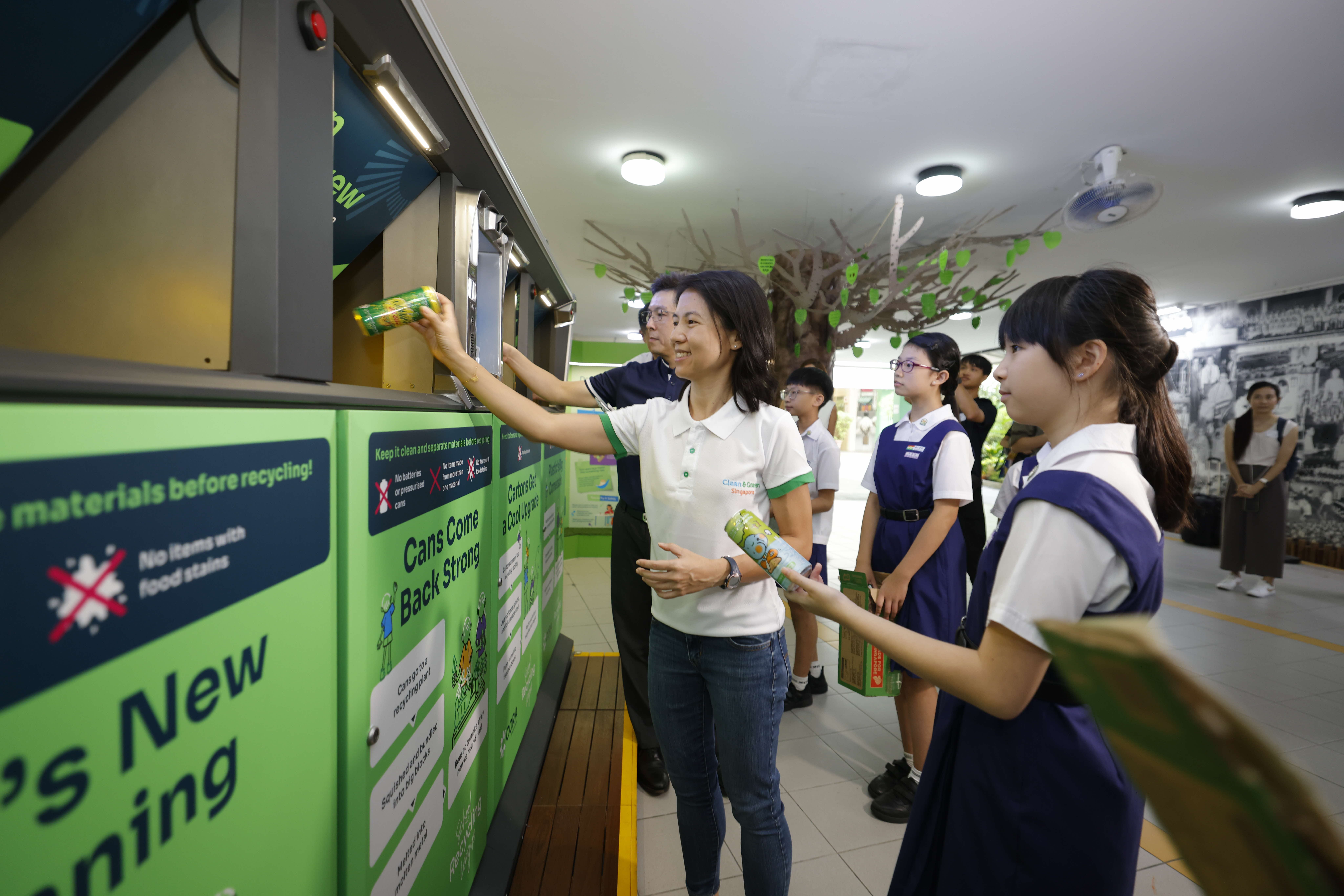 Students showcasing a recycling receptacle.
