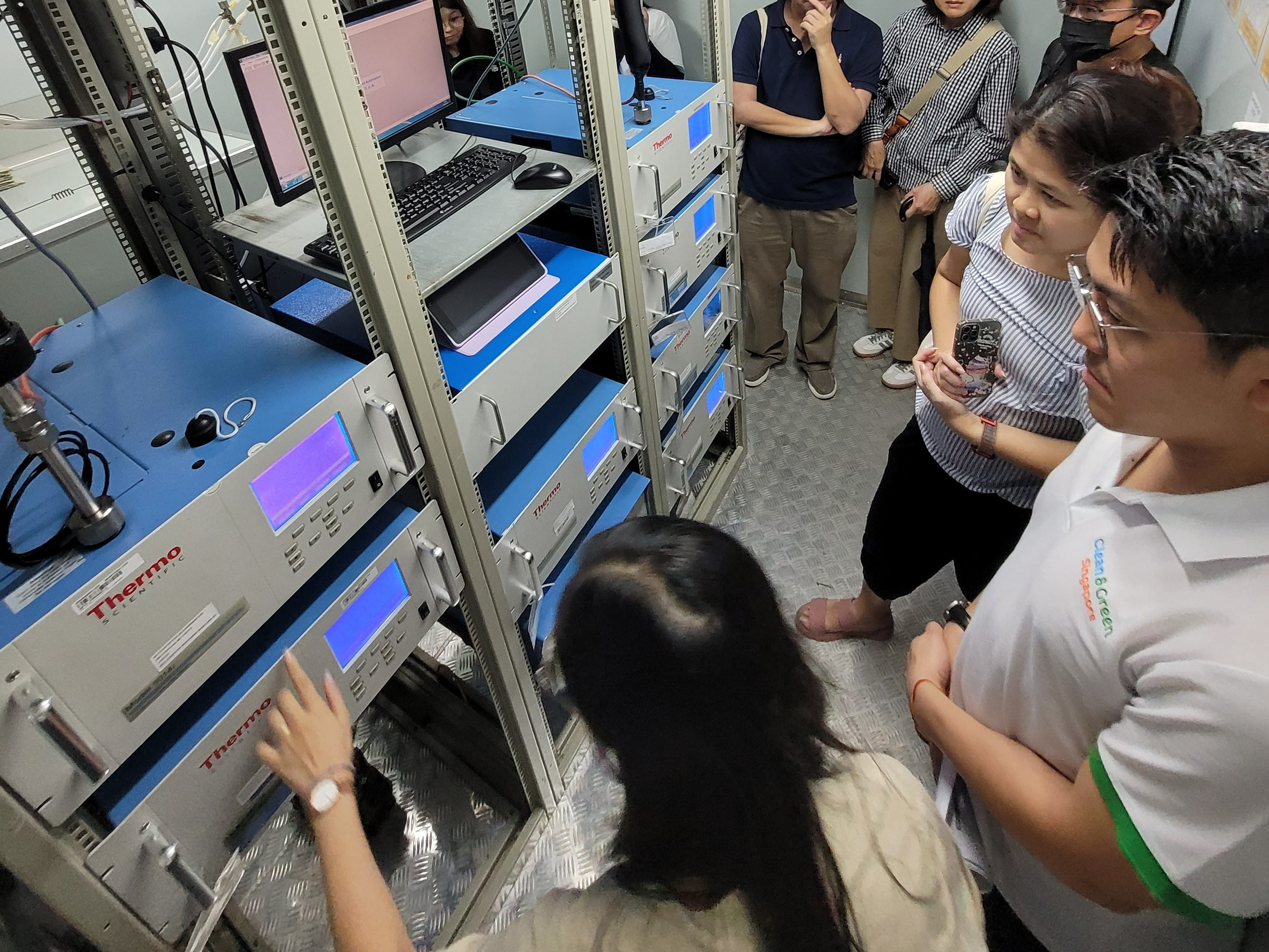 Several people gather around rack-mounted instruments.