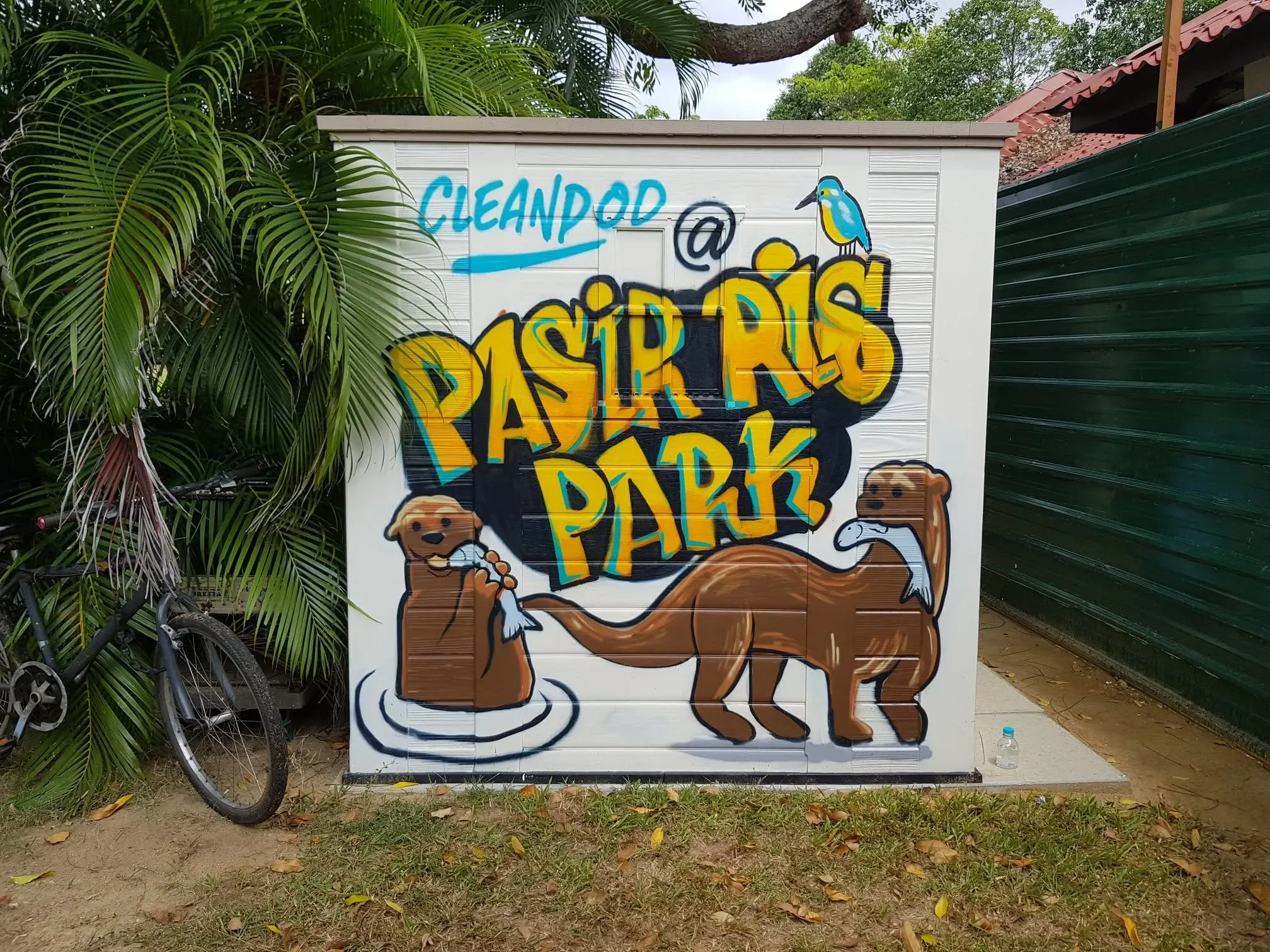 A CleanPod unit at Pasir Ris Park, decorated with vibrant graffiti-style artwork featuring illustrations of otters and a kingfisher bird, with the words 'CleanPod @ Pasir Ris Park' prominently displayed.