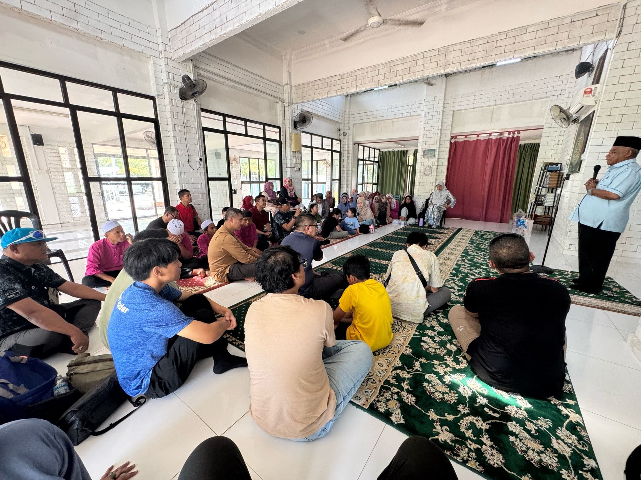 LKM members seated inside an orphanage hall listening to a sharing session by a speaker standing at the front.