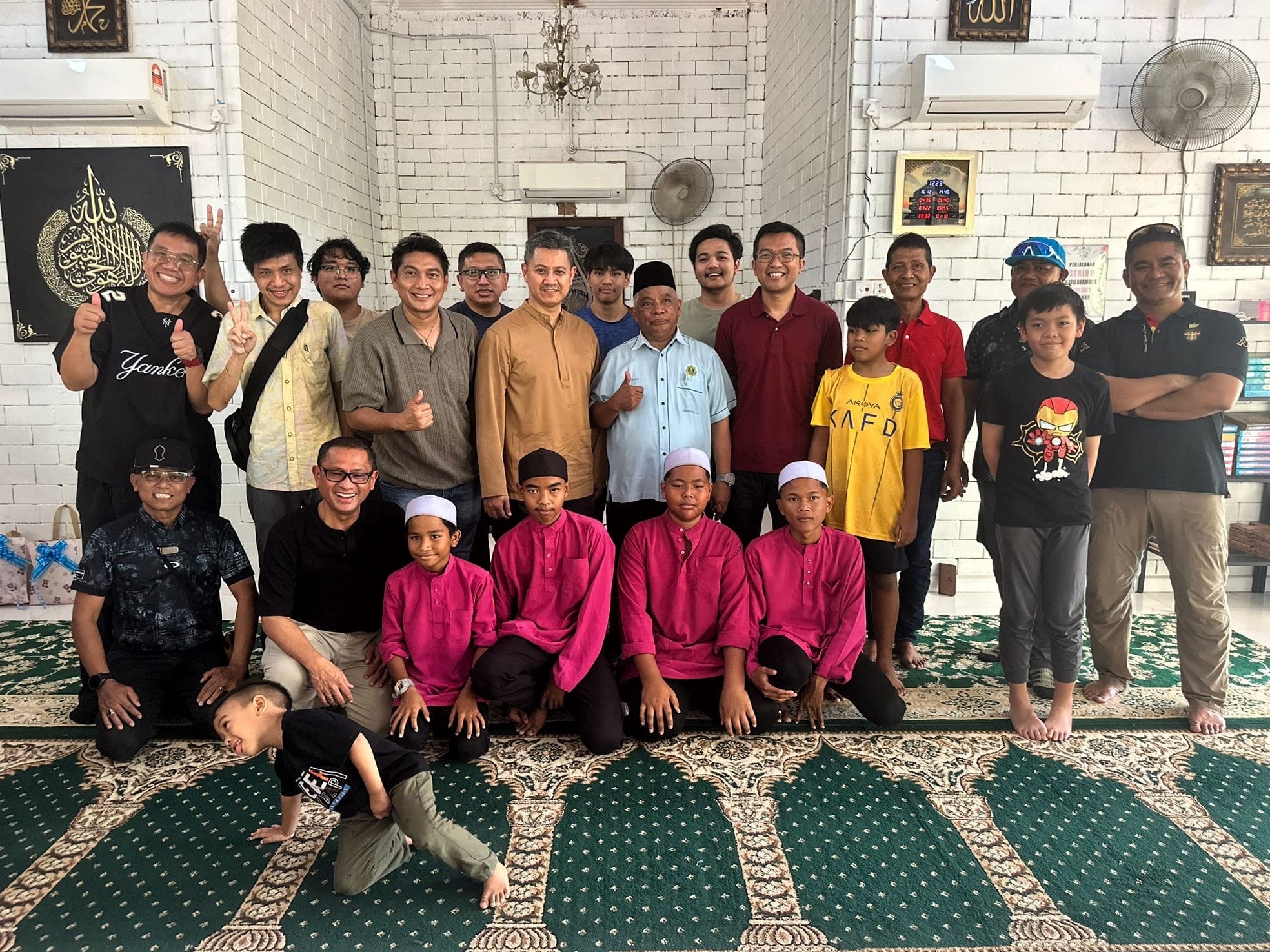 Group photo of LKM male members, orphanage staff and children gathered inside the orphanage hall.