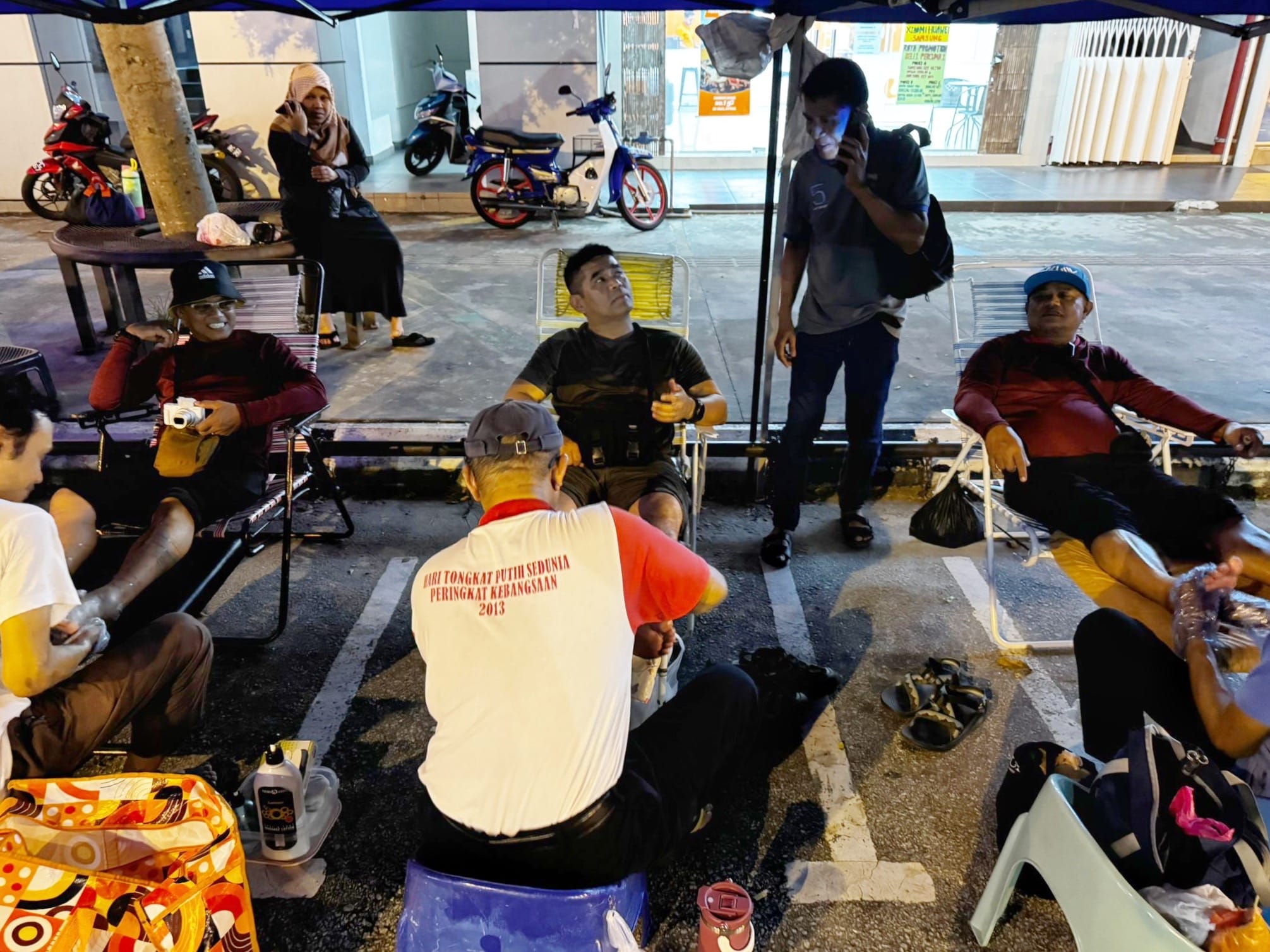 Members relaxing at an outdoor seating area while receiving traditional leg massage treatments.