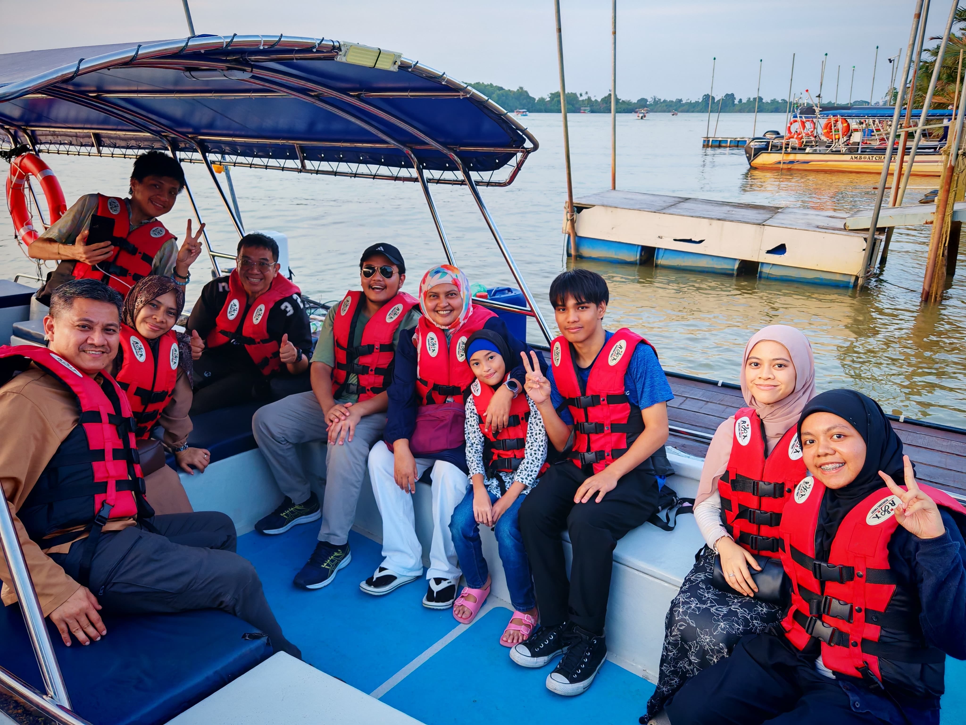 LKM members wearing life jackets and seated on a river cruise boat while posing for a group photo at the jetty.
