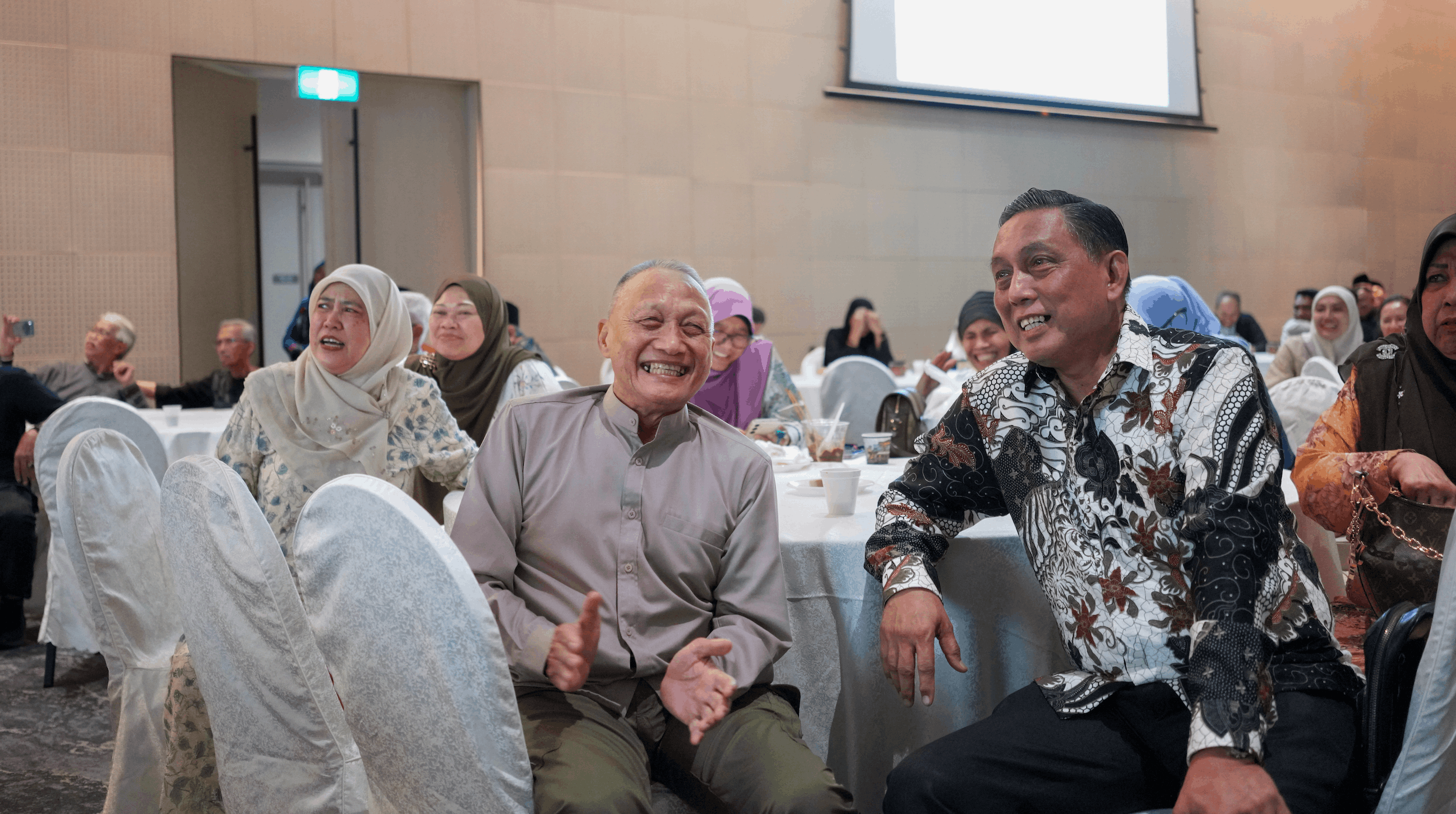 Two men and a woman seated together, smiling and laughing during an event.