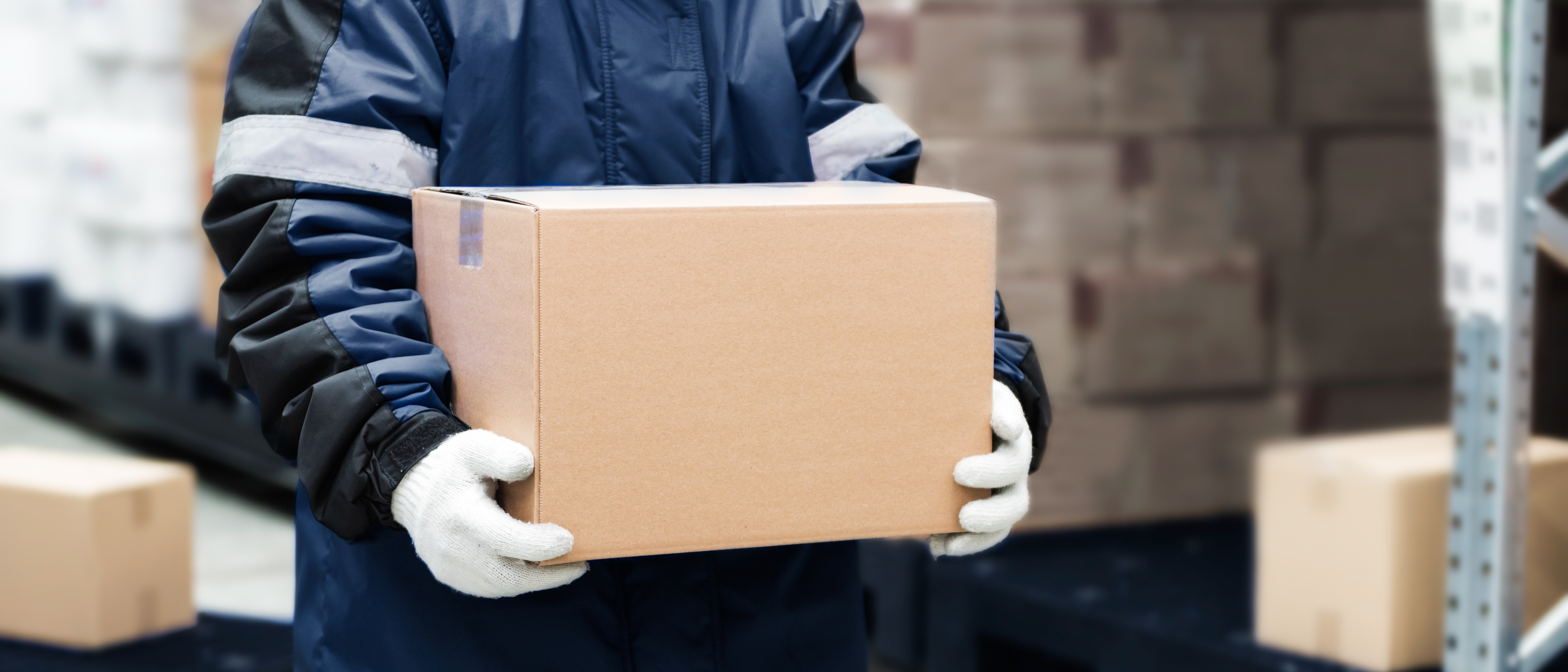 gloved person in blue uniform carrying a box