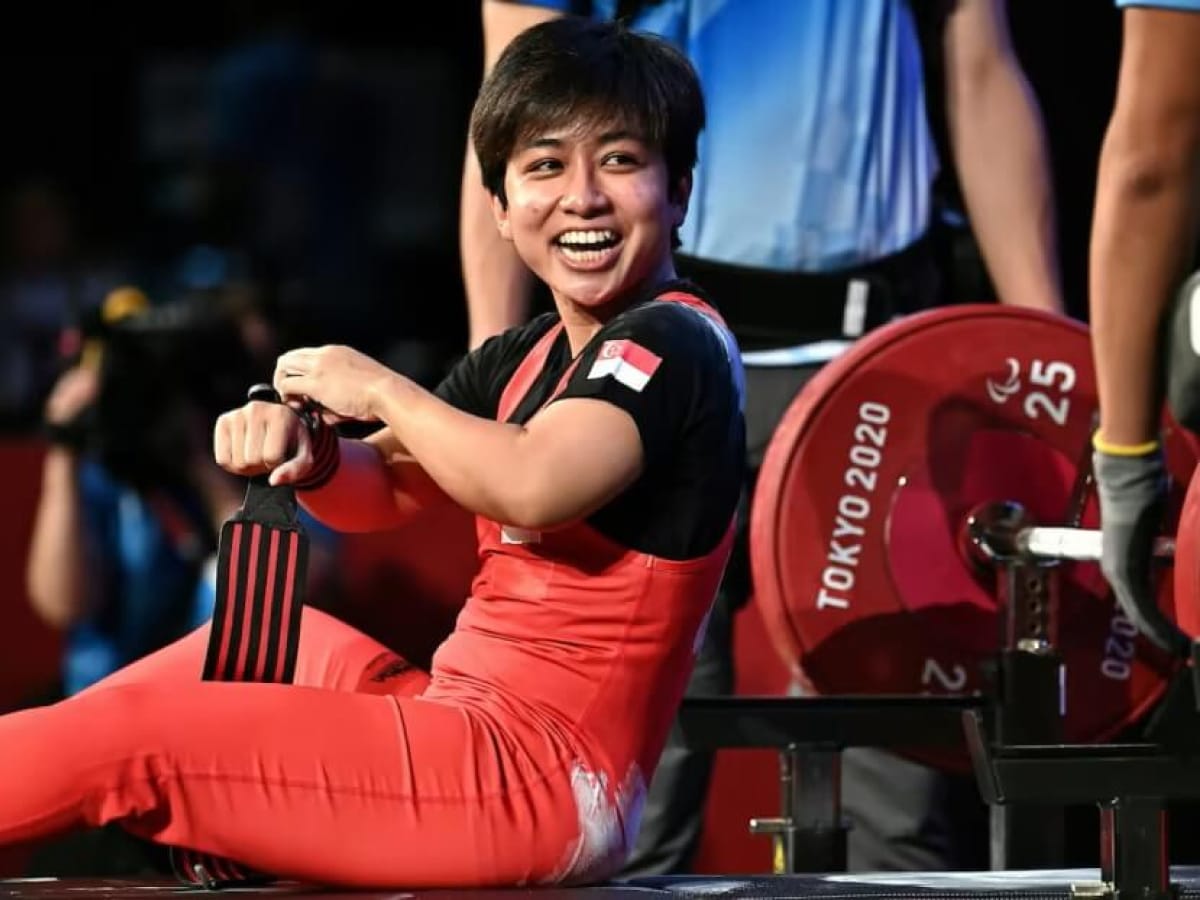 A smiling Singaporean powerlifter wraps her wrist before the Tokyo 2020 Paralympics.