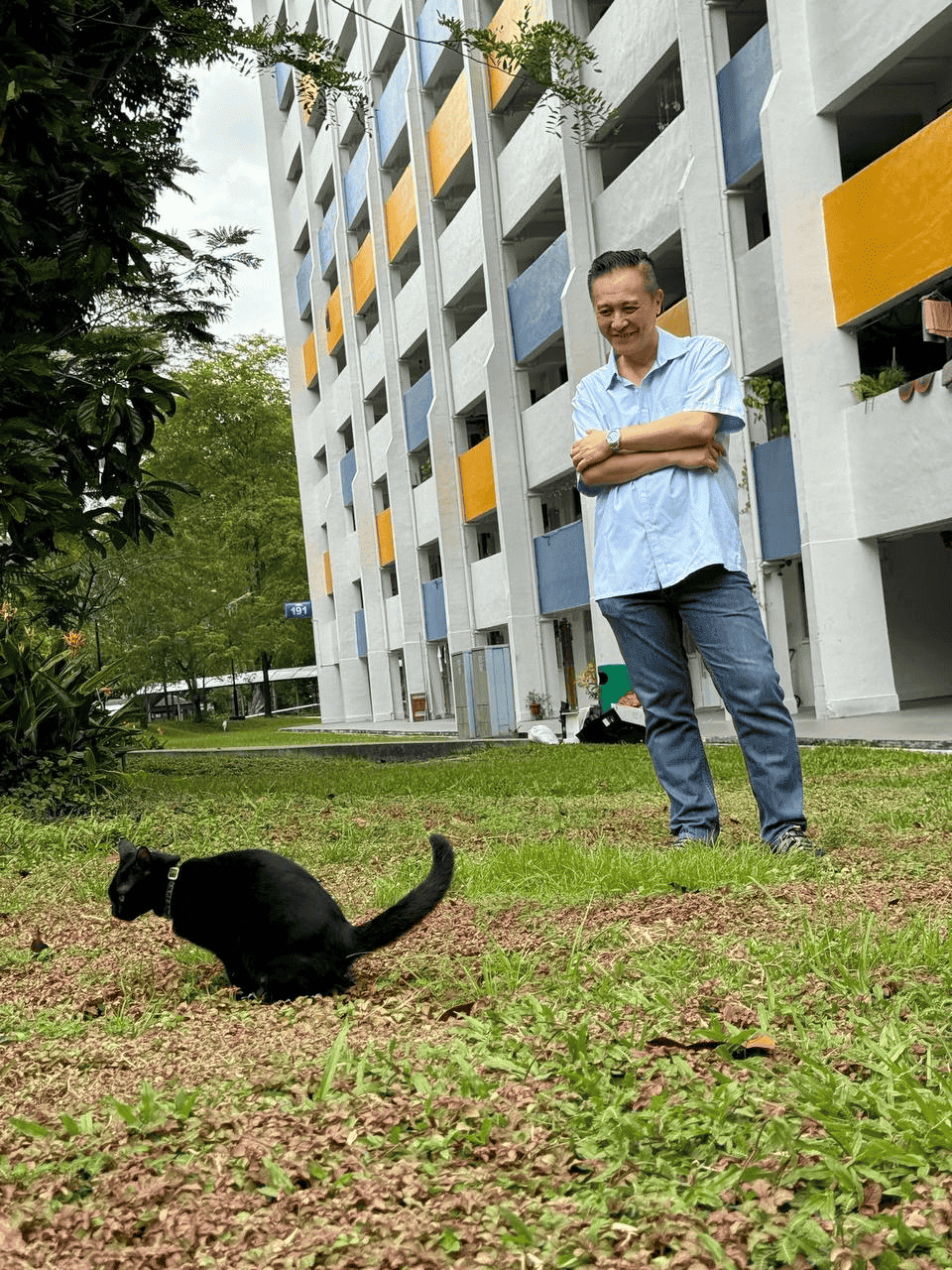 Clarence Ho smiling down at a community cat