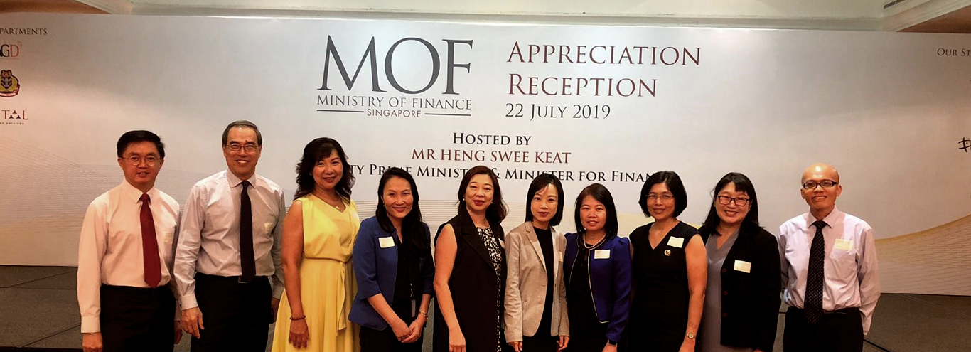 Ten people pose together in front of a Ministry of Finance Singapore Appreciation Reception banner dated 22 July 2019.