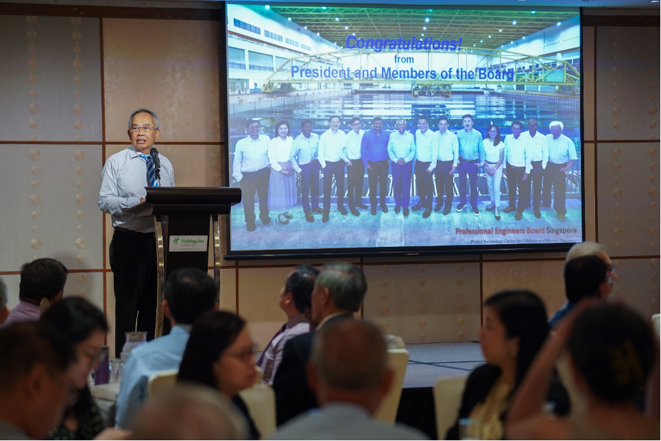 Man speaks at a podium before a seated audience, with a congratulations slide from Professional Engineers Board Singapore projected behind him.