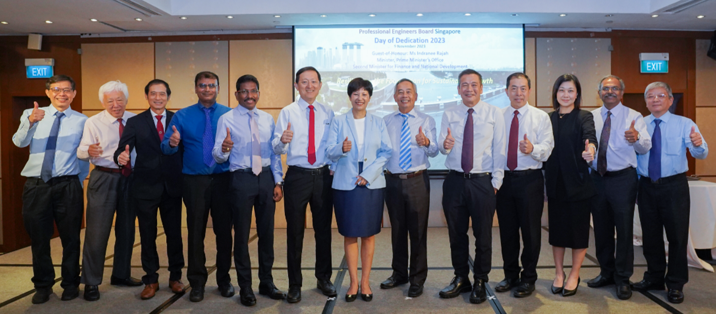A group of thirteen people in formal attire give thumbs up at the Professional Engineers Board Singapore Day of Dedication 2023.