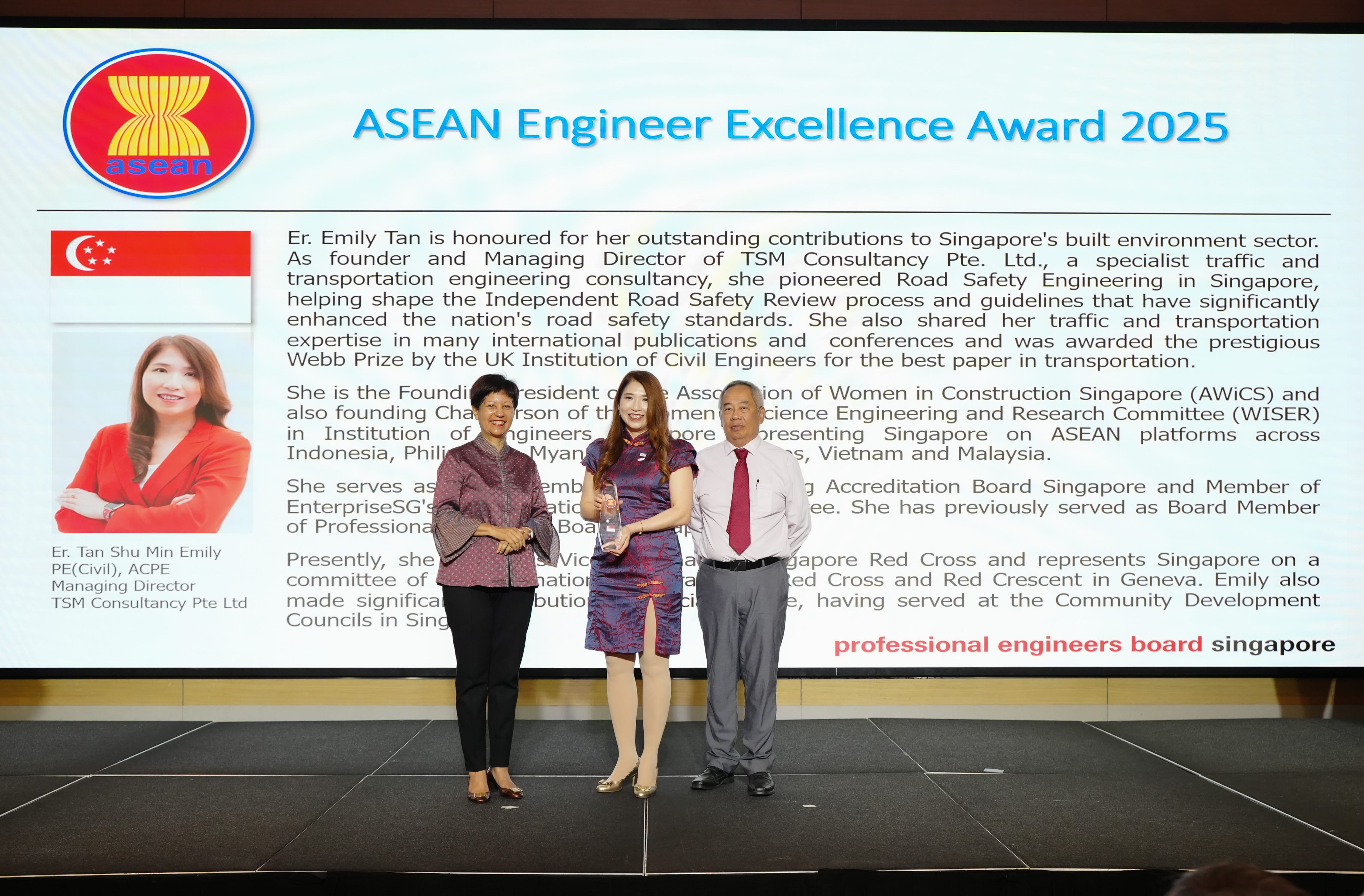 Three people stand on a stage in front of a screen showing the ASEAN Engineer Excellence Award 2025 for Er. Emily Tan.