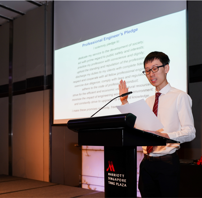 Man in white shirt and red tie reciting the Professional Engineer's Pledge at a Marriott Singapore podium.