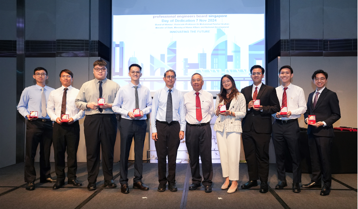 Ten people stand in a row holding red award boxes at a Professional Engineers Board Singapore Day of Dedication event.