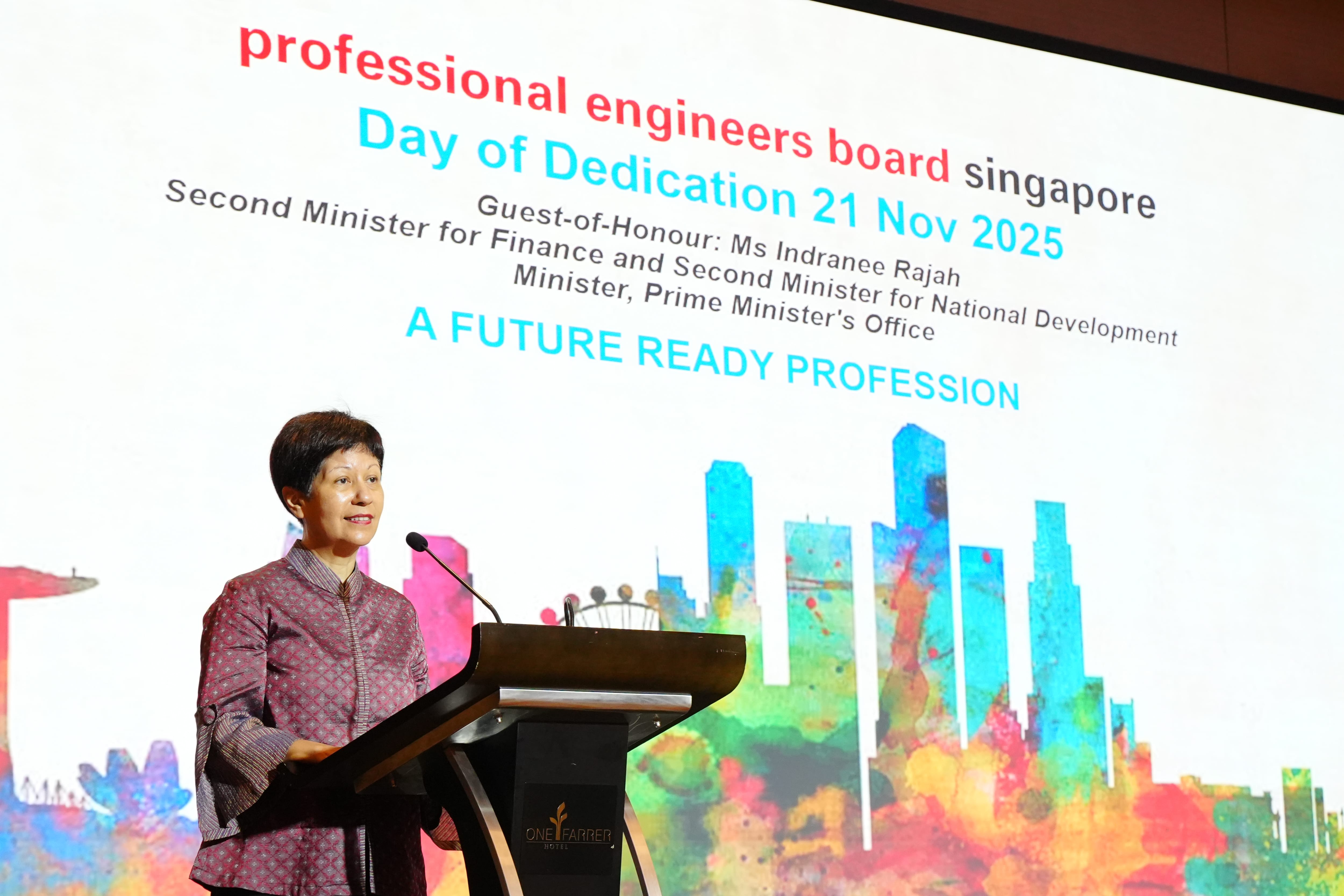Woman speaks at a podium before a screen showing Professional Engineers Board Singapore Day of Dedication 21 Nov 2025.