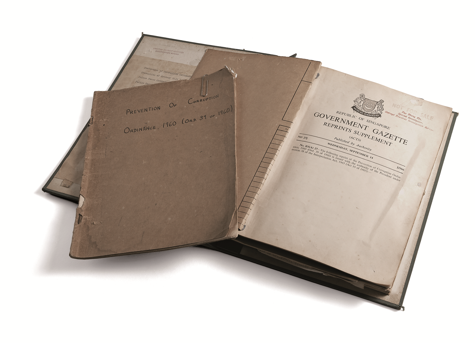 Aged documents including a 1960 Prevention of Corruption Ordinance booklet and a Republic of Singapore Government Gazette.