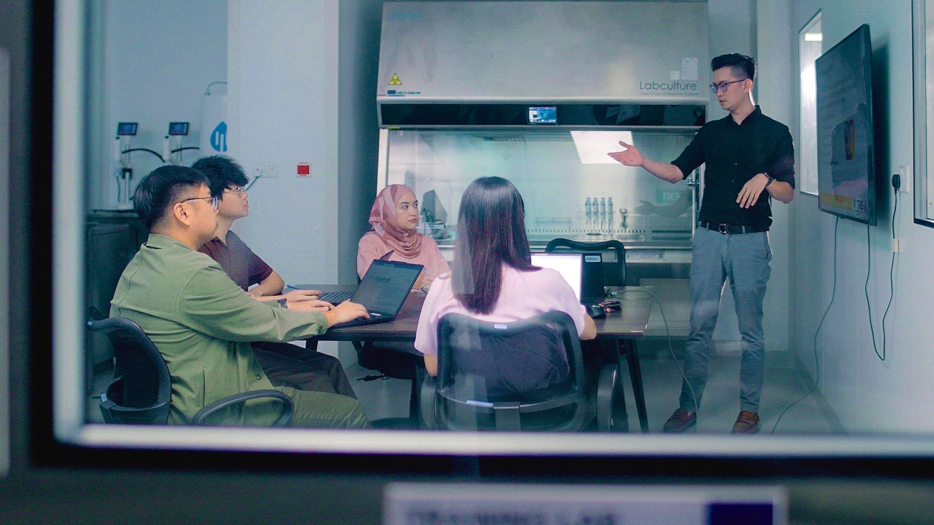 A training session taking place where a trainer is presenting to a group of learners in a lab..