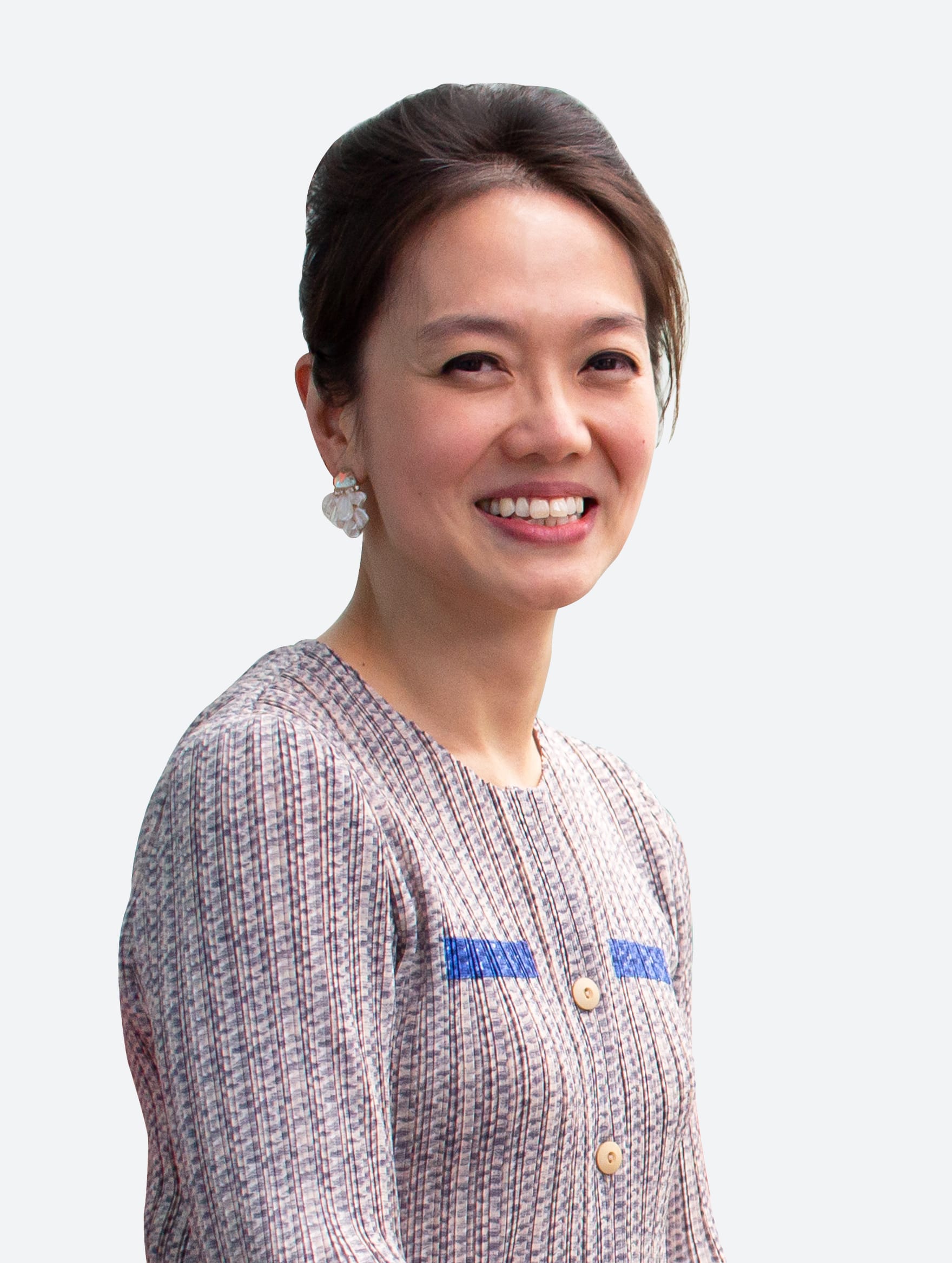 A smiling woman with dark hair up, wearing flower earrings and a striped blouse with blue accents, on a light background.