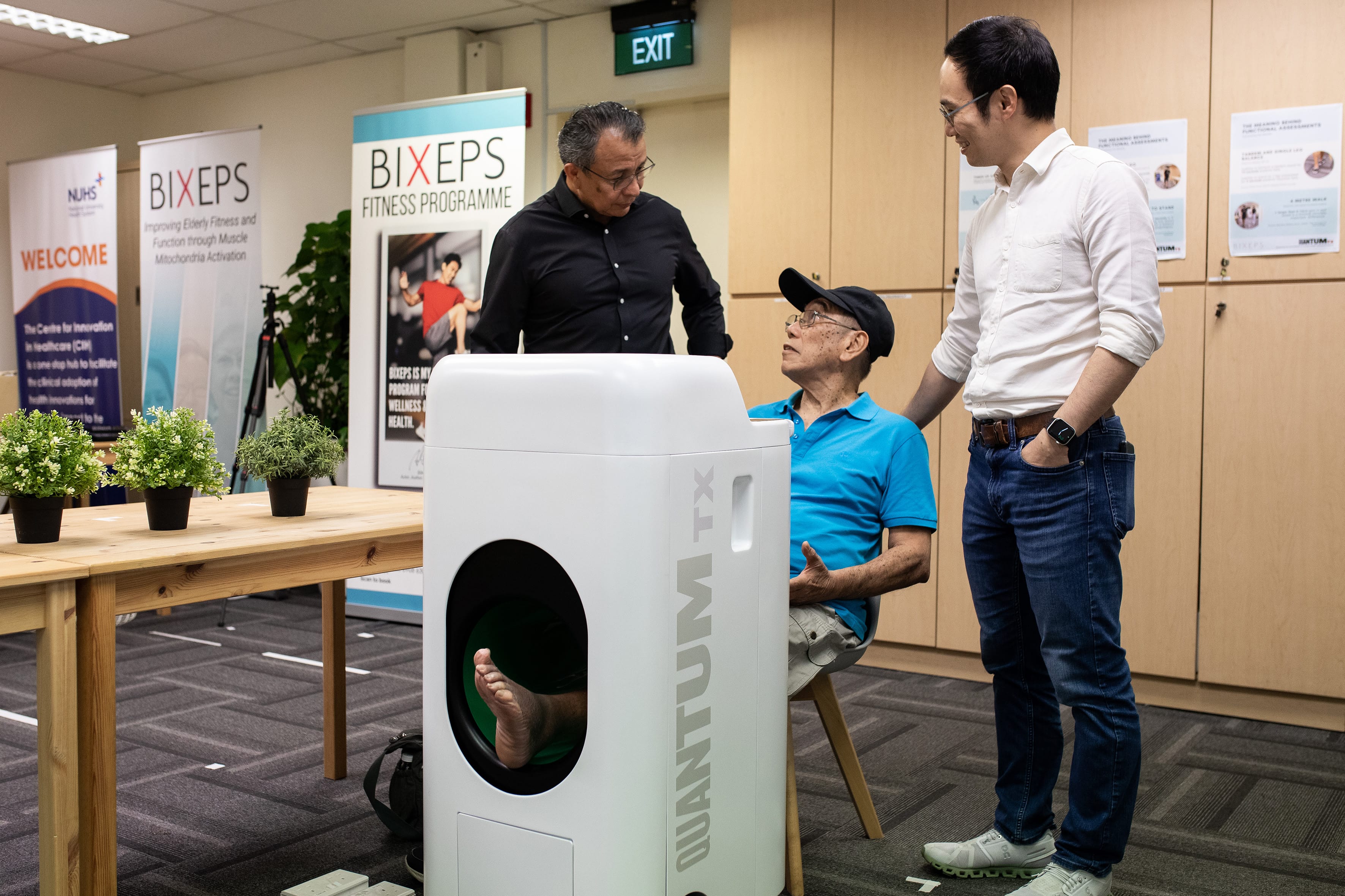 2 men standing next to an elderly patient using the medical device