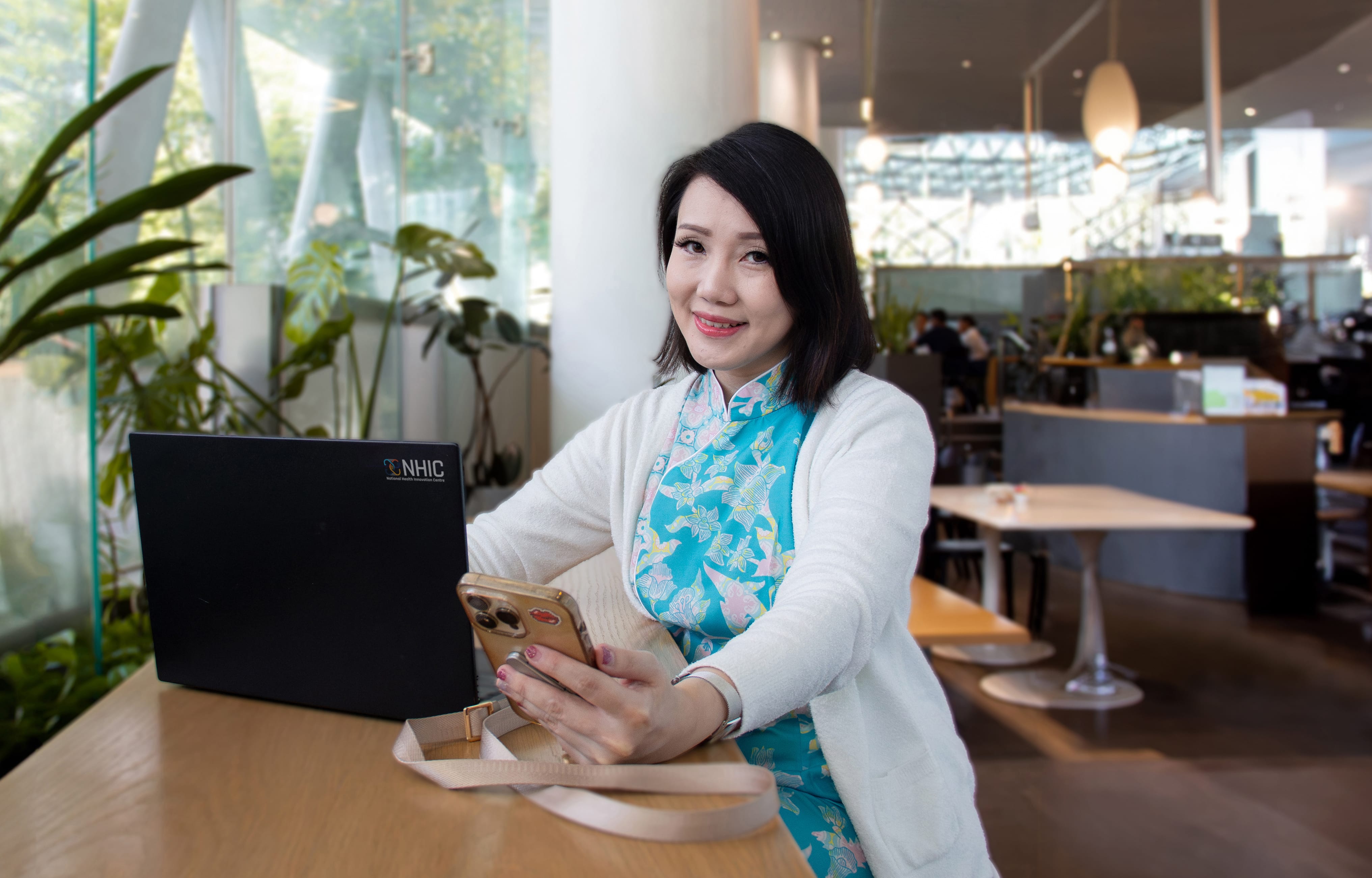 A lady with short haor holding phone and laptop