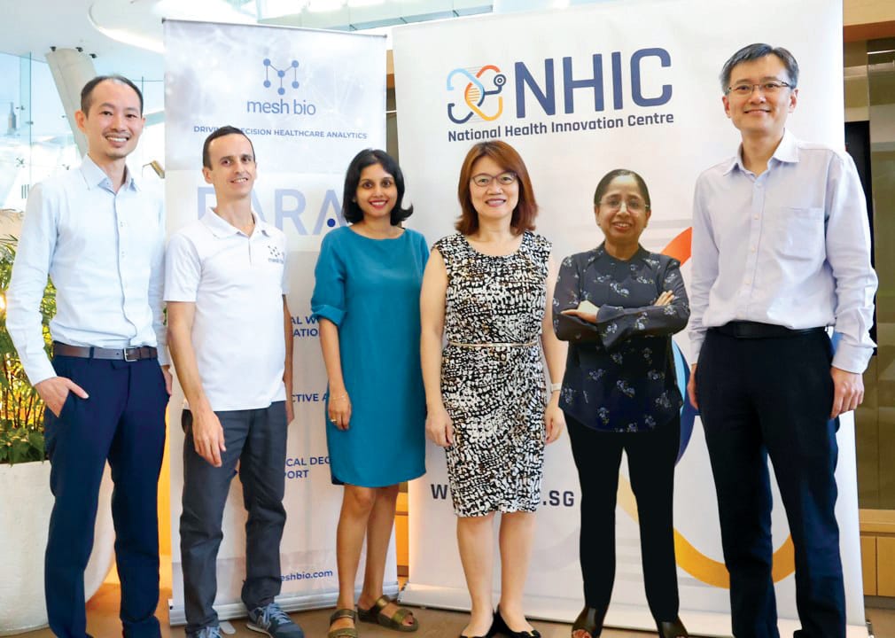 A group of six people standing in front of NHIC banner