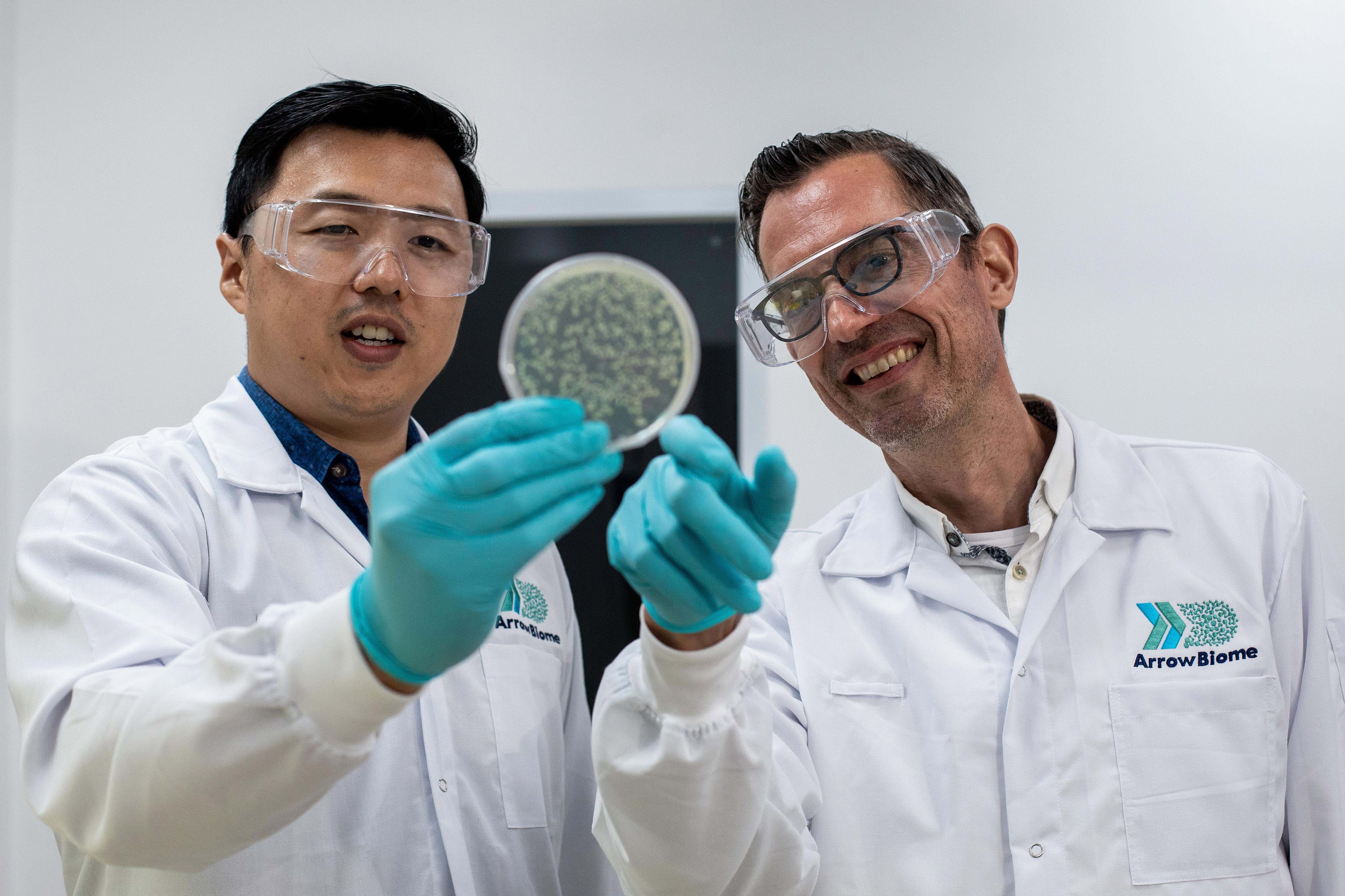 Two men in lab coat holding culture plates