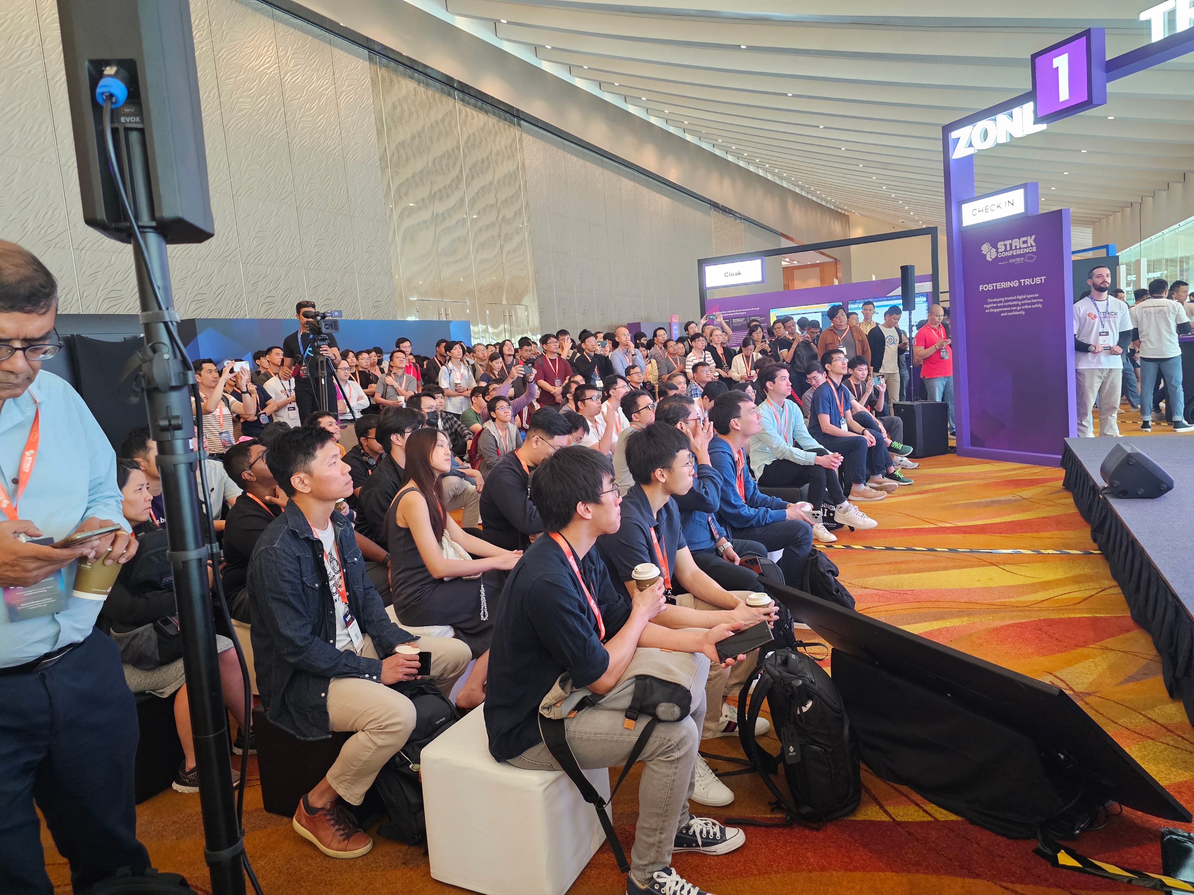 Large crowd seated and standing at the STACK Conference, watching a presentation in a modern convention hall.