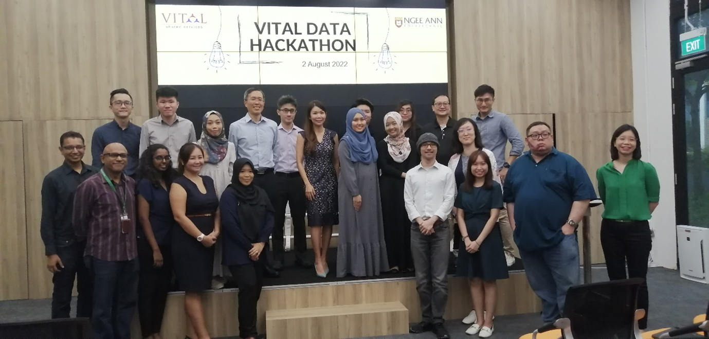 Group of about 20 people posing in front of a screen displaying Vital Data Hackathon, 2 August 2022.