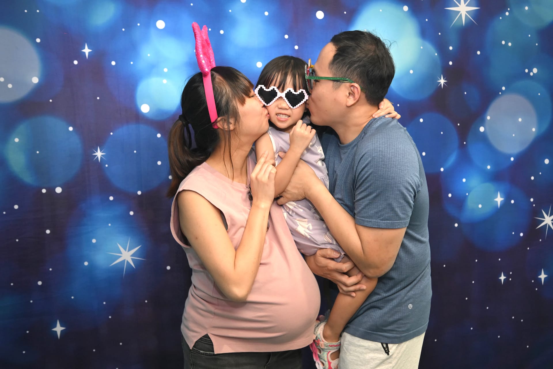 Parents kissing their daughter's cheeks.
