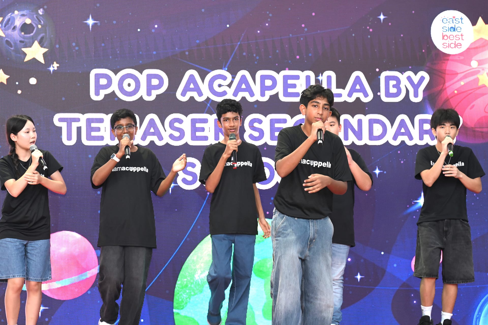 A group of teenagers singing and dancing on stage.