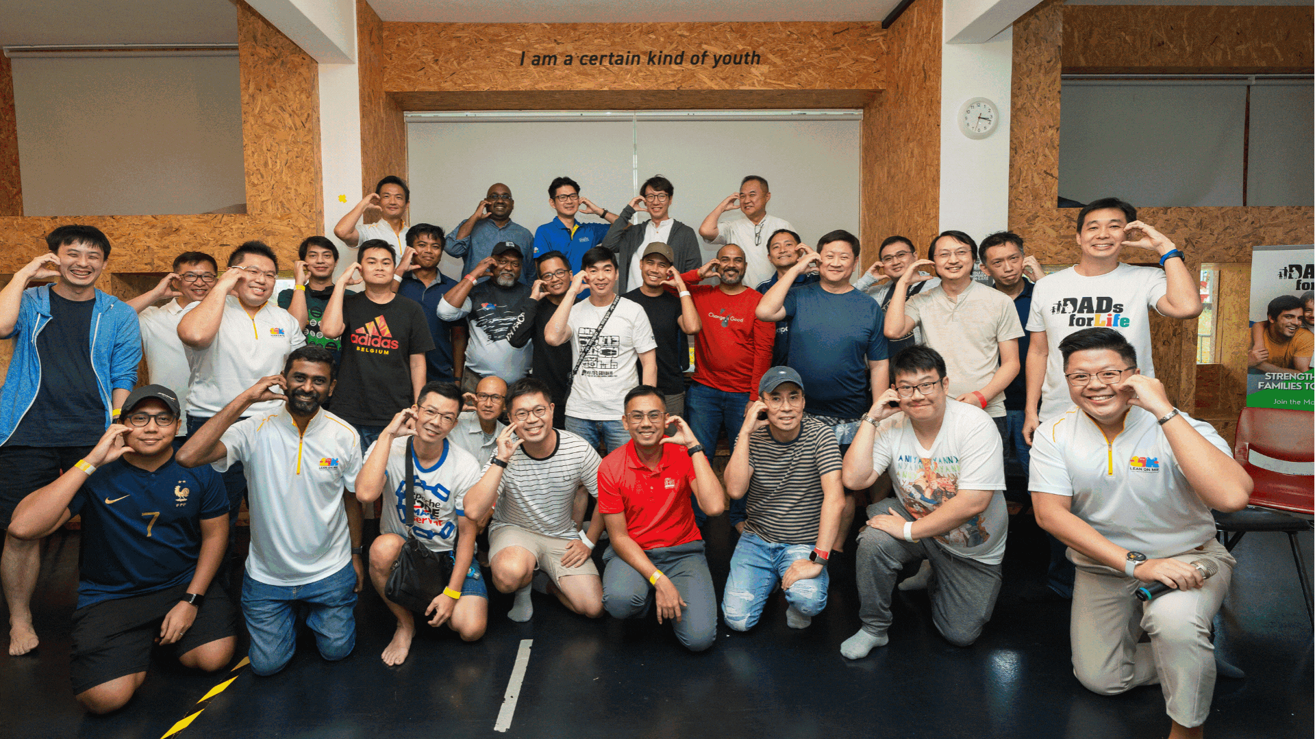 Group of men posing indoors, many making a hand gesture near the eye; slogan above reads I am a certain kind of youth.