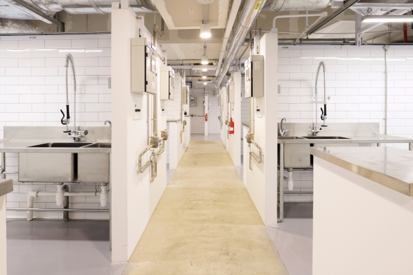 Industrial kitchen with sinks and white brick walls.