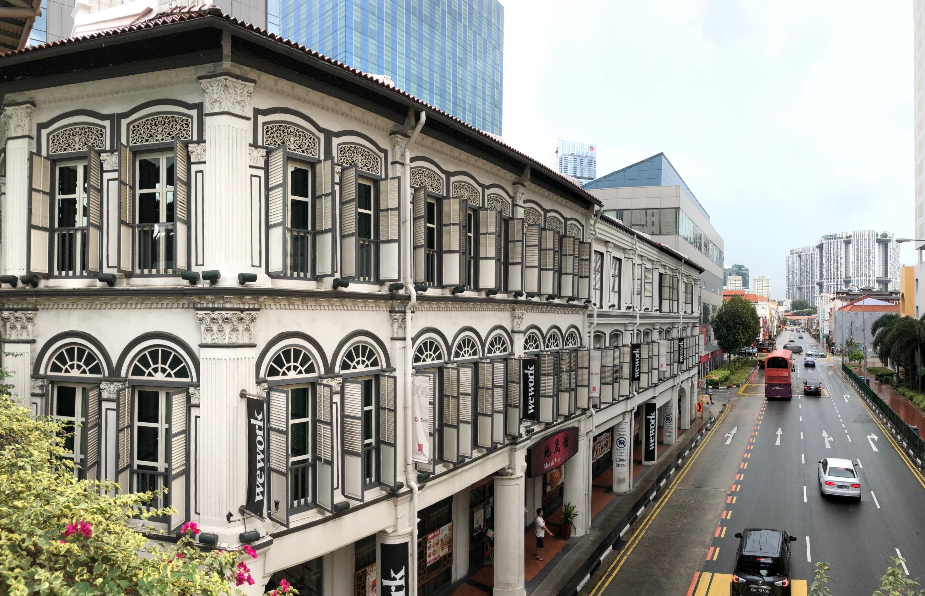 A row of conserved shophouses with intricate architectural details, located in Singapore's Chinatown district, with modern buildings in the background.