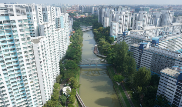 Aerial view of a city with high-rise buildings flanking a canal with a blue bridge.