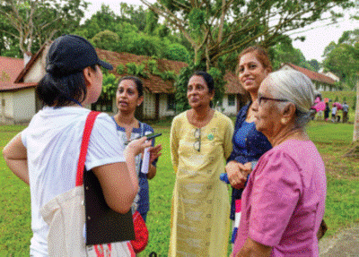 A guide speaks with a group of women outdoors near heritage buildings