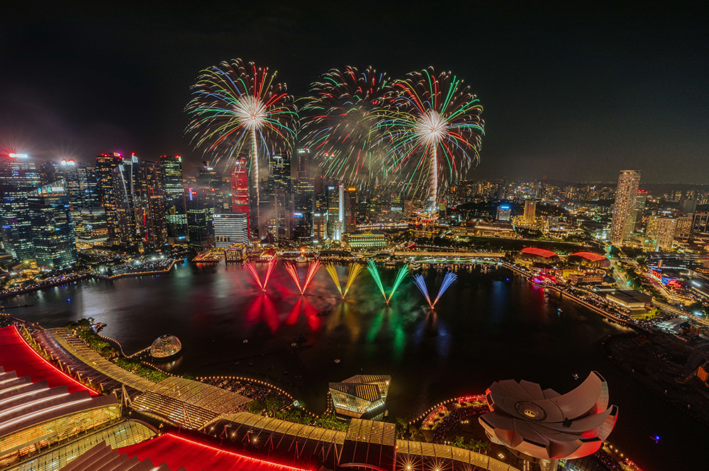 Fireworks over Singapore skyline reflecting in the water at night.